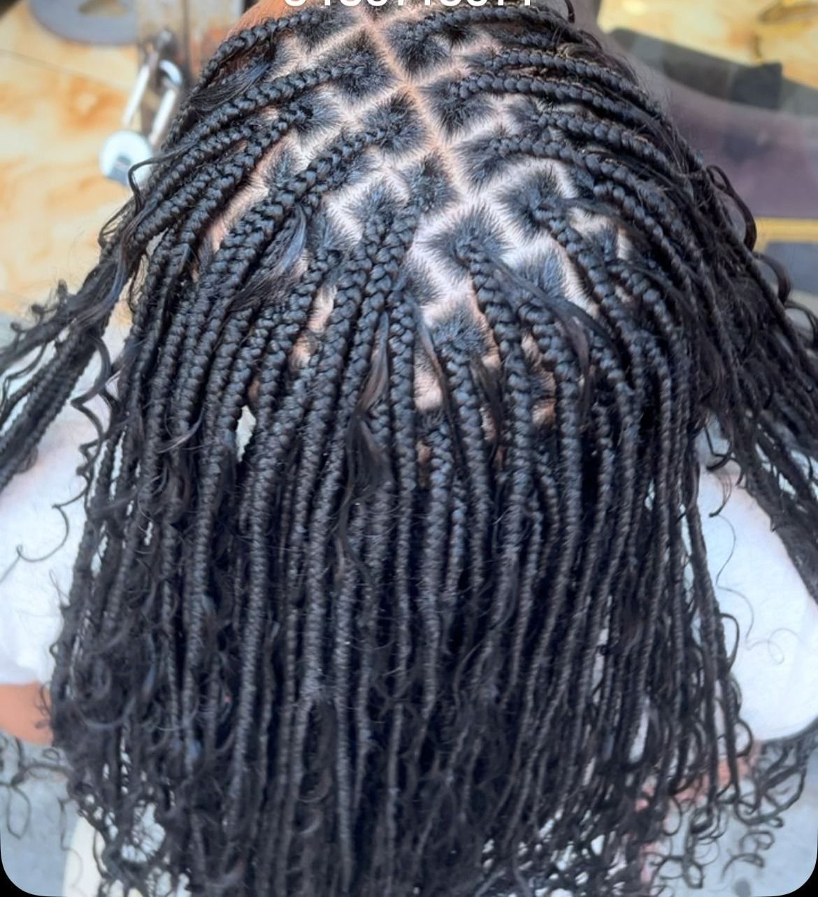 The back of a woman 's head with braids and curly hair.