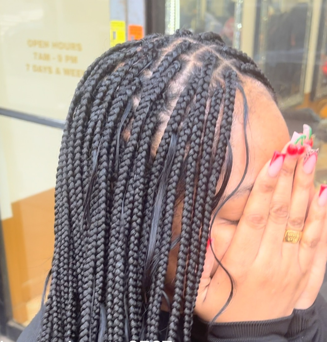 A woman with braids covering her face with her hands