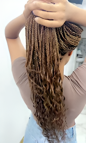 A woman with braids in her hair is holding her hair in a bun.