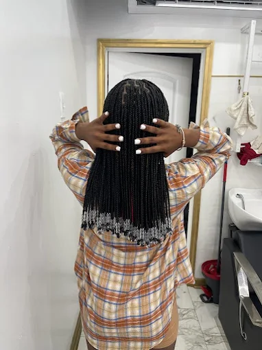 A woman in a plaid shirt is standing in a bathroom with her hands on her hair.