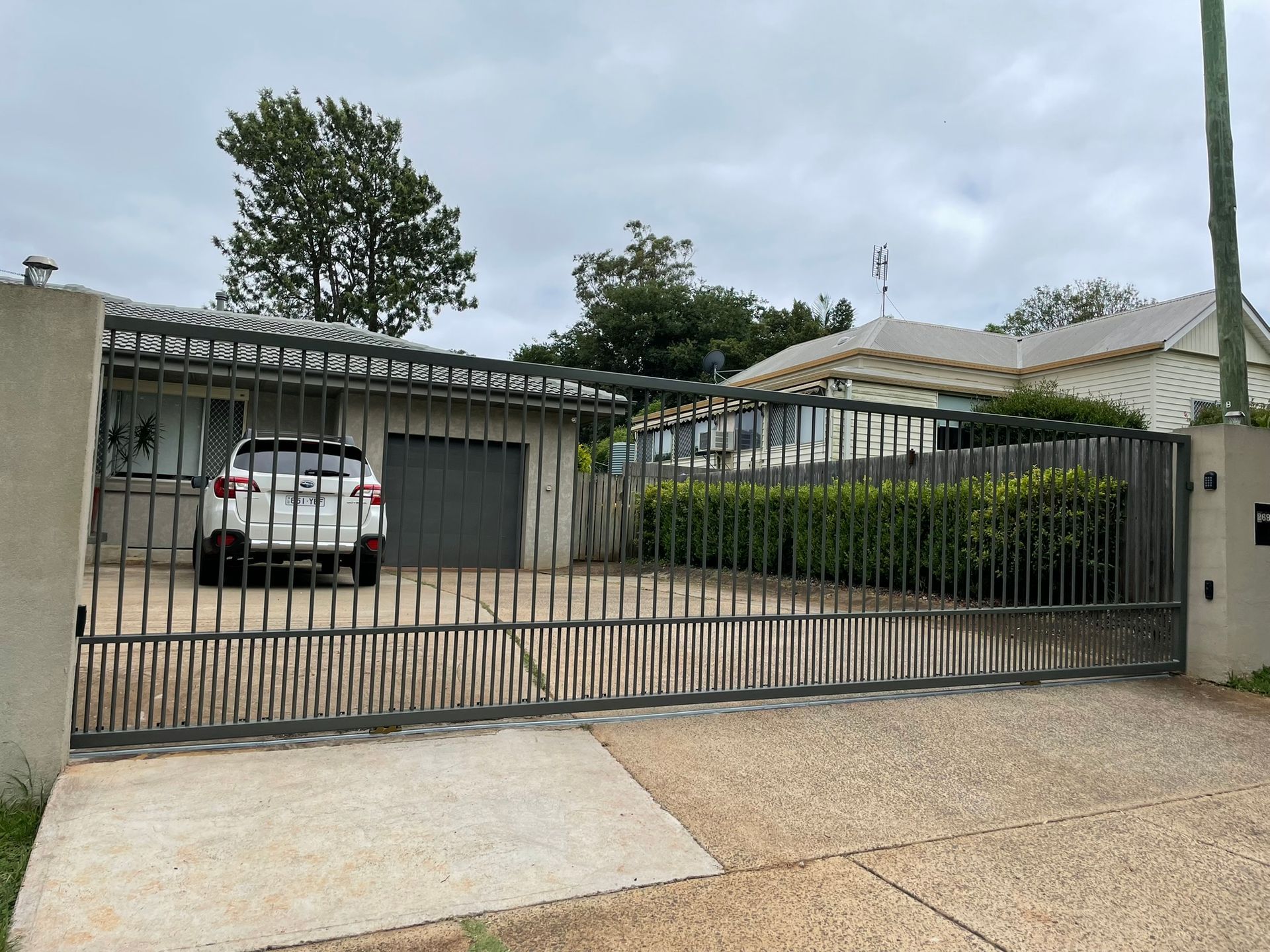 A car is parked in front of a house behind a gate