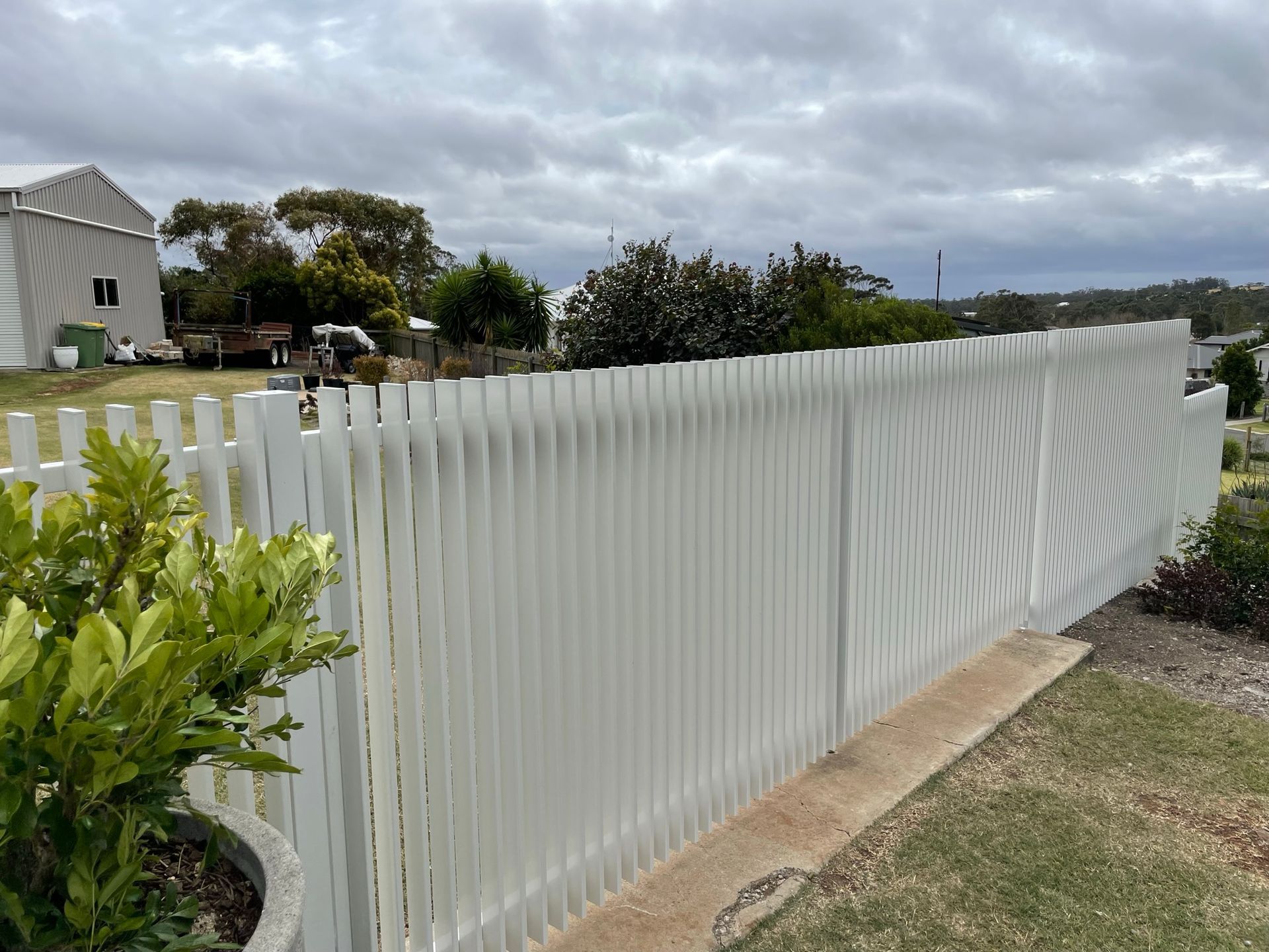 A white picket fence surrounds a lush green yard.