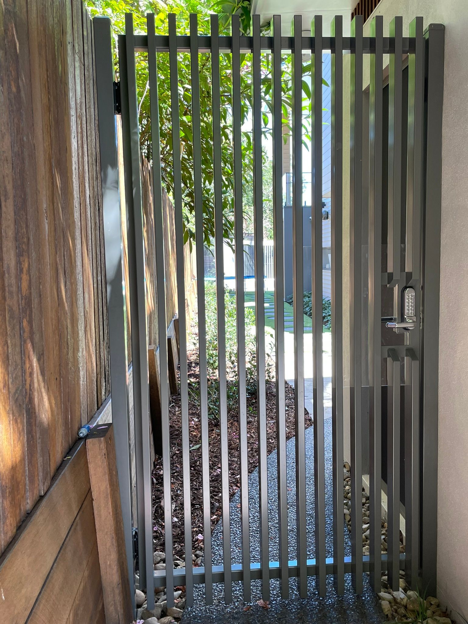 A metal gate is leading to a narrow alleyway.