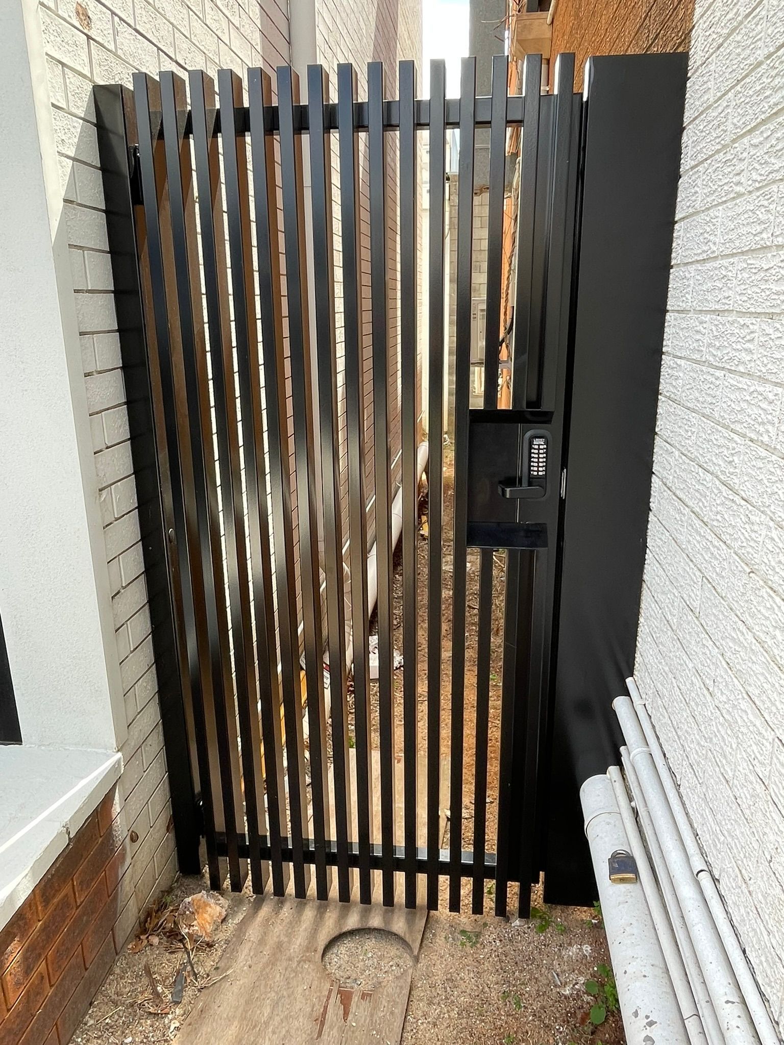 A black gate is sitting in the corner of a building.