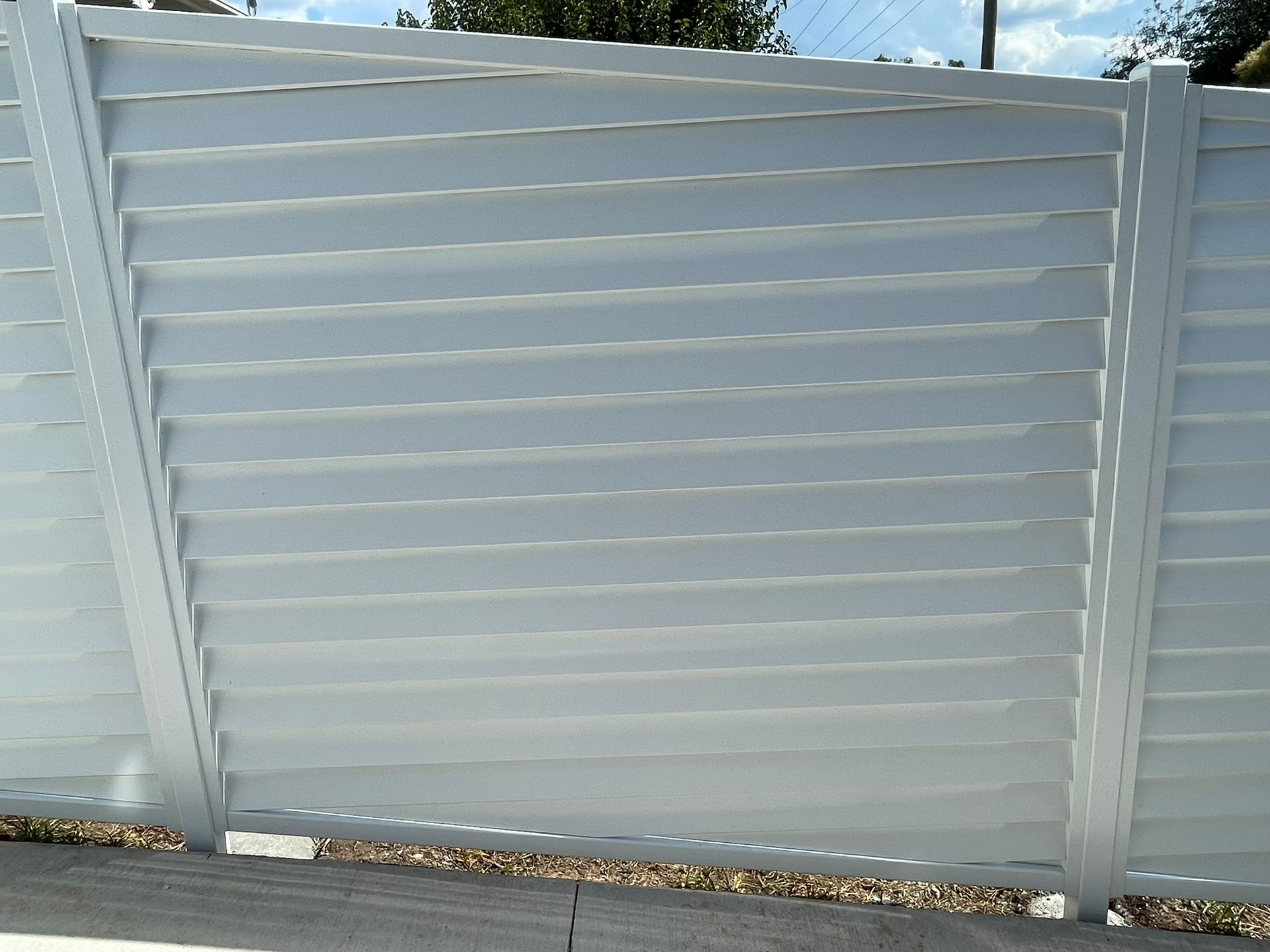 A close up of a white fence with a blue sky in the background