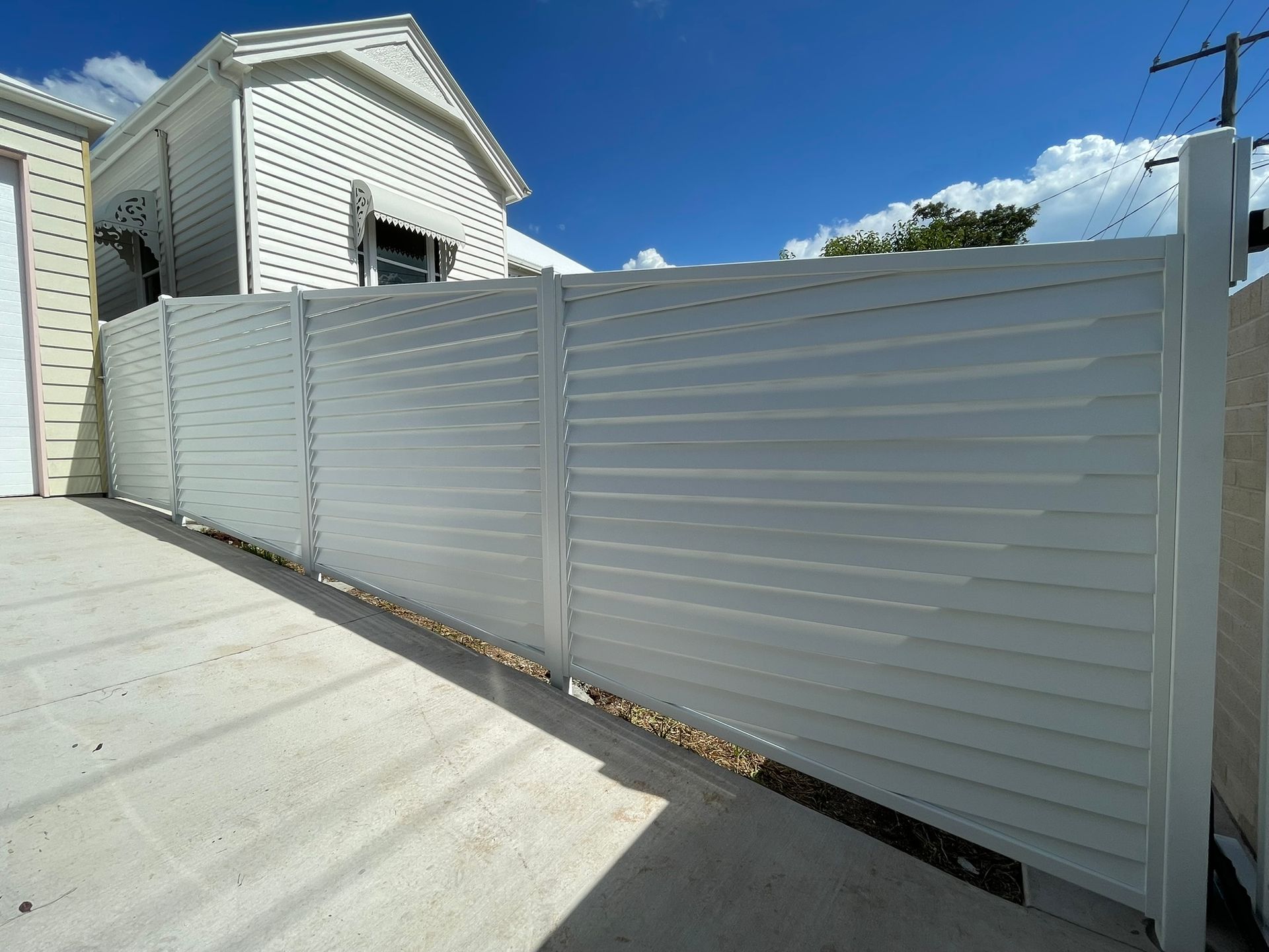 A white fence is sitting in front of a house.