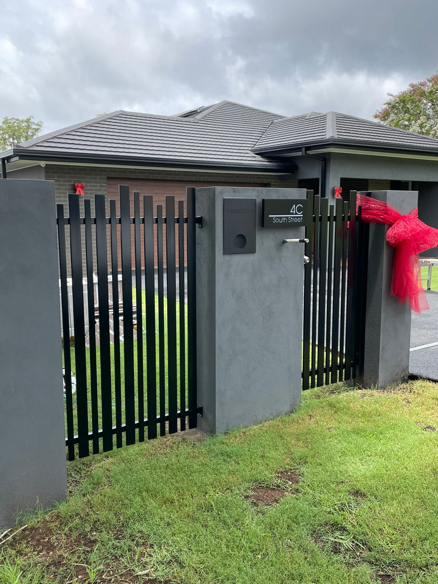 A black fence is surrounding a house with a red bow on it.