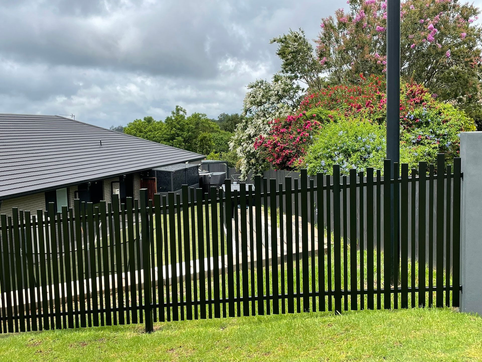 A black fence is surrounding a house in a residential area.