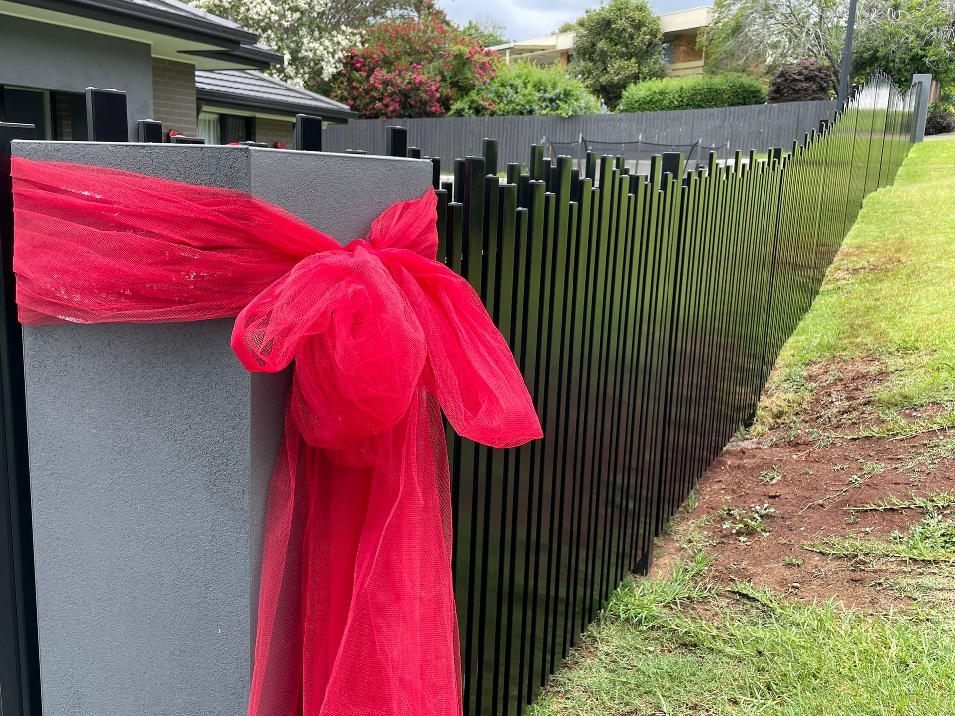 A black fence with a red bow on it.