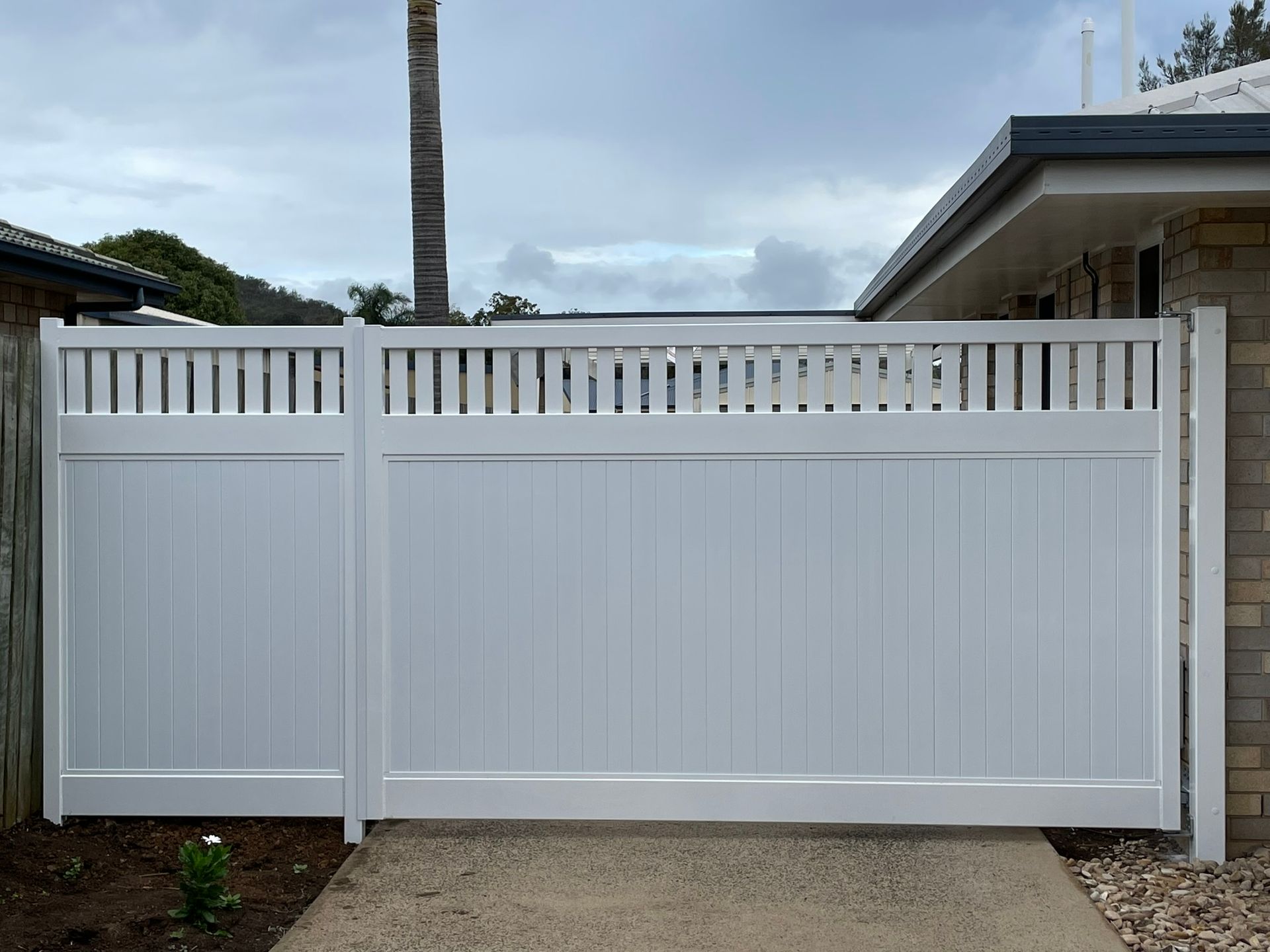 A white fence is sitting in front of a house.