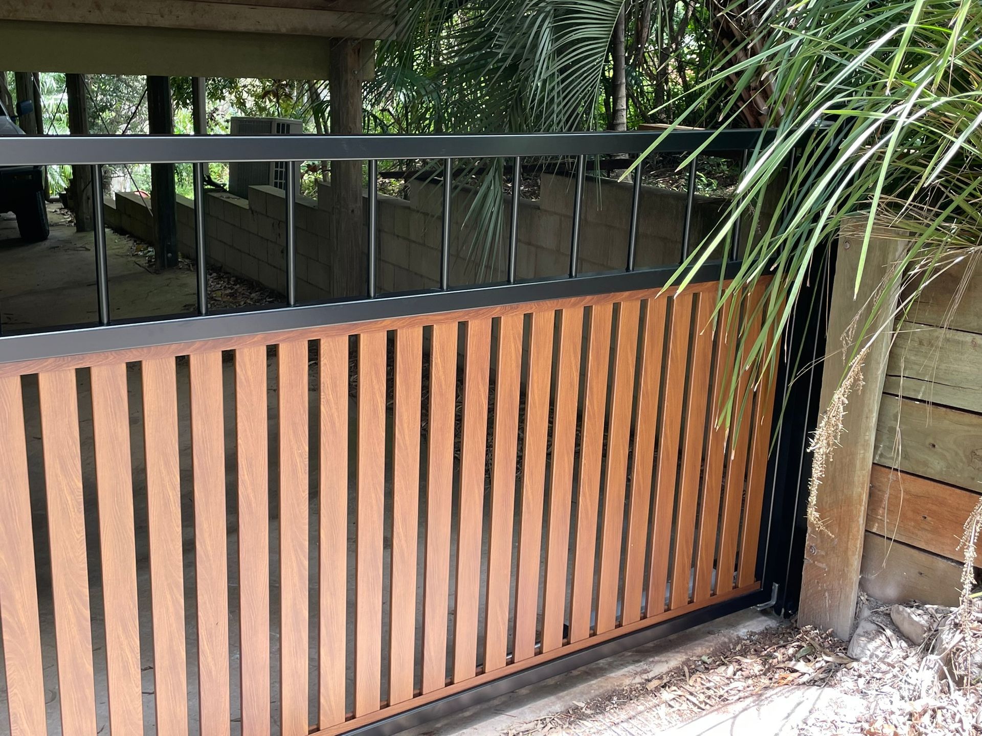 A wooden fence with a black railing is surrounded by trees.