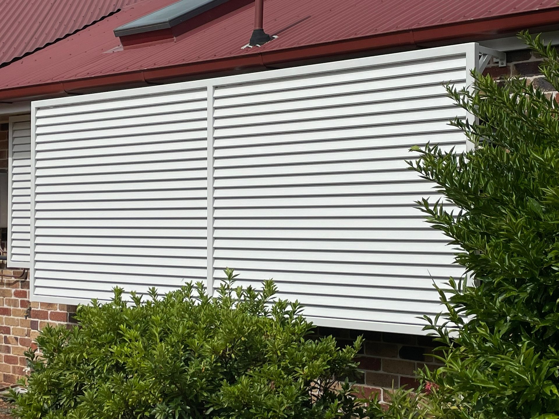 A house with a red roof and white shutters on the windows