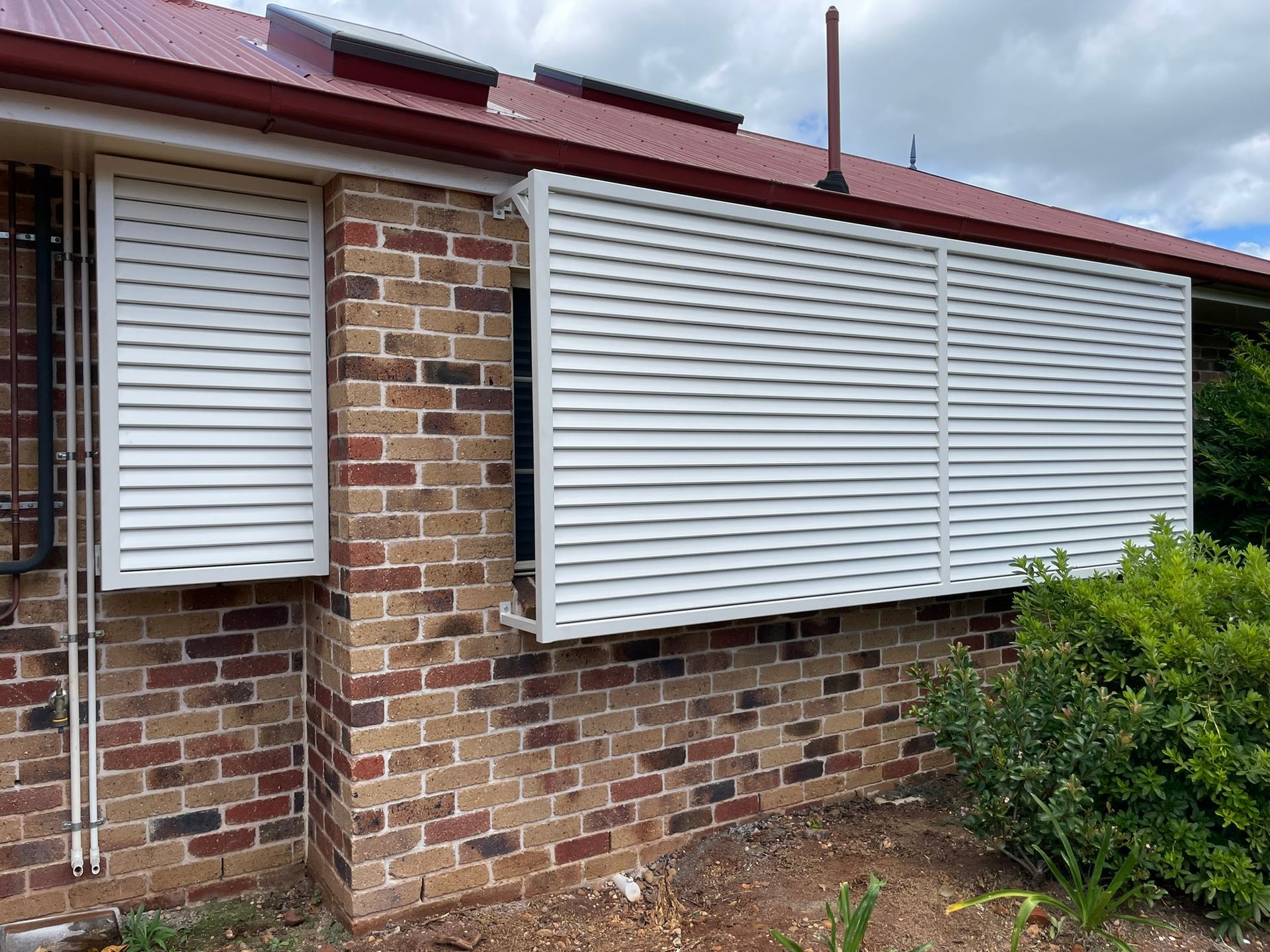 A brick house with a white shutter on the side of it.