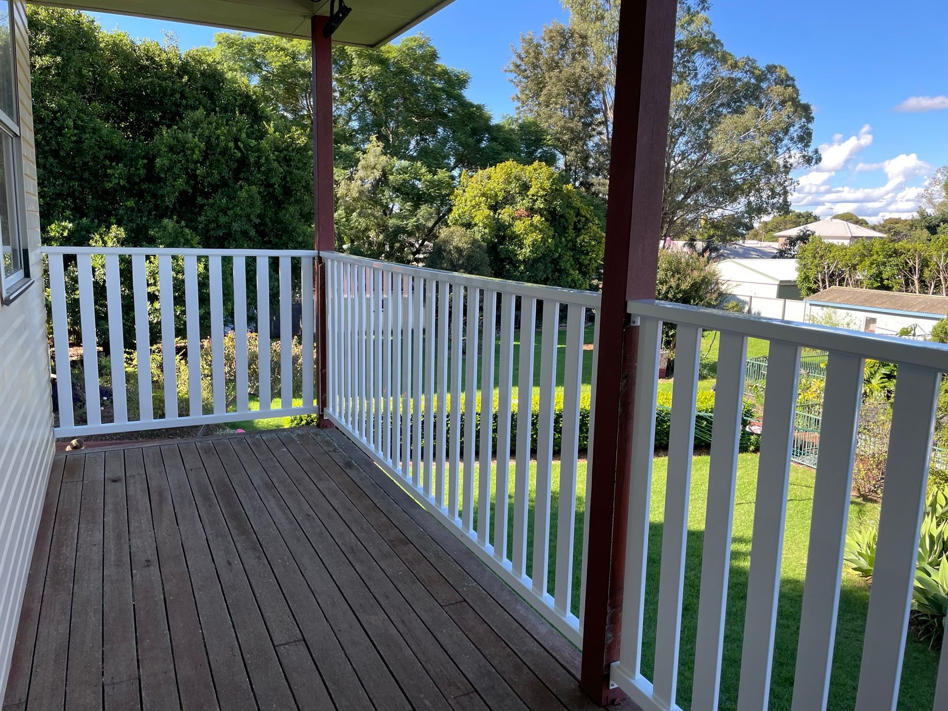 An empty veranda with a white railing and trees in the background
