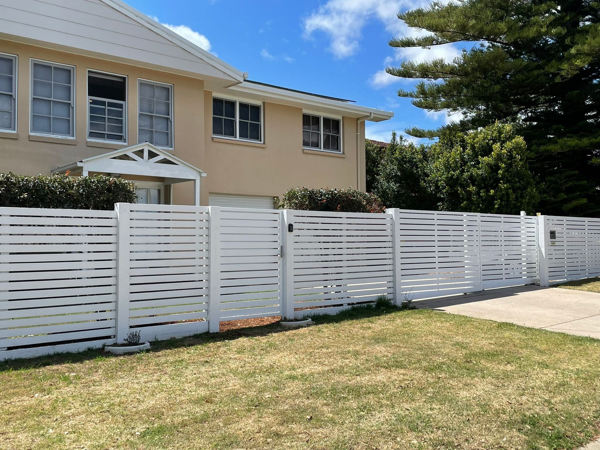 A white fence is in front of a house