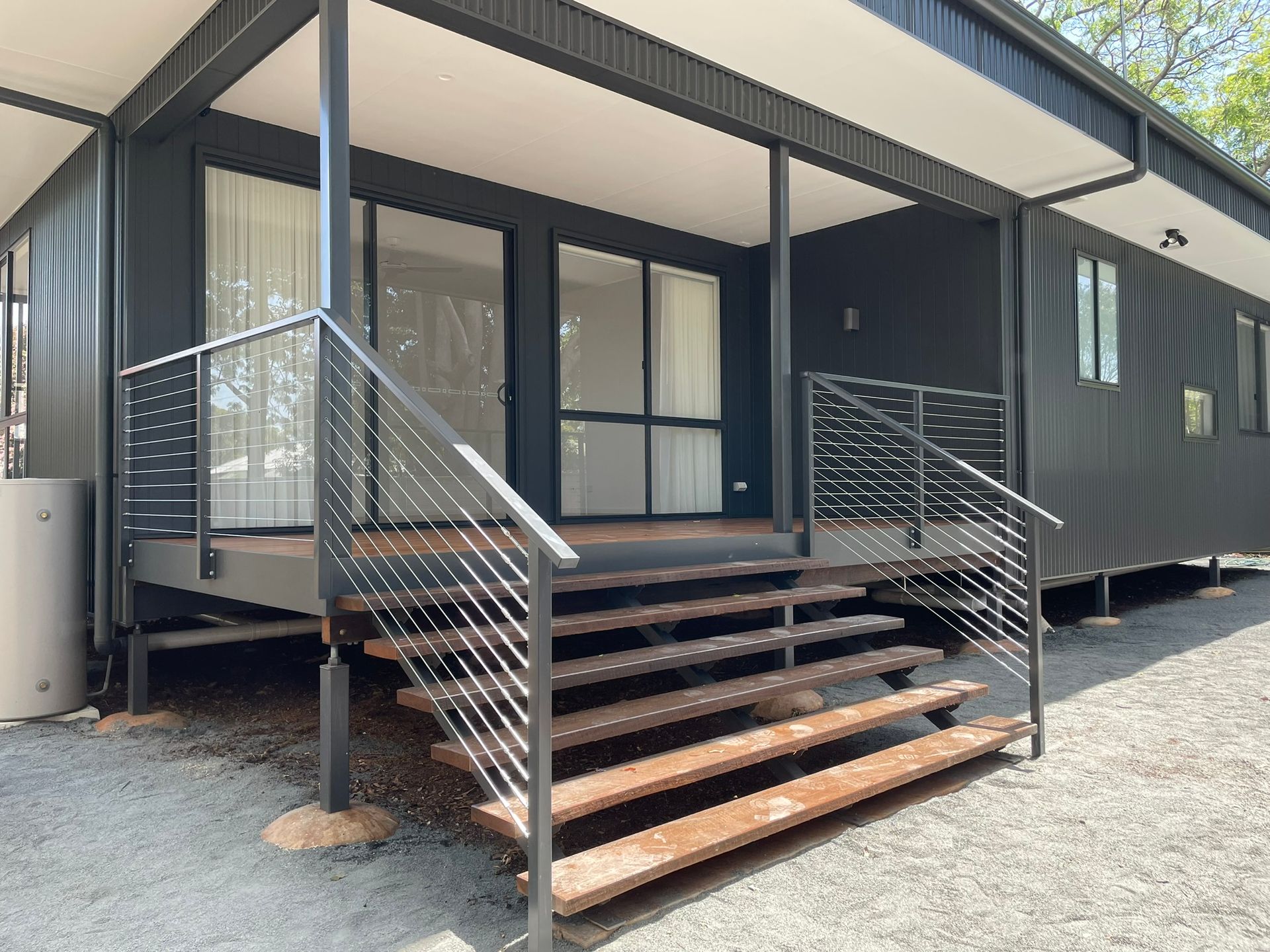 A black house with wooden stairs and a metal railing.