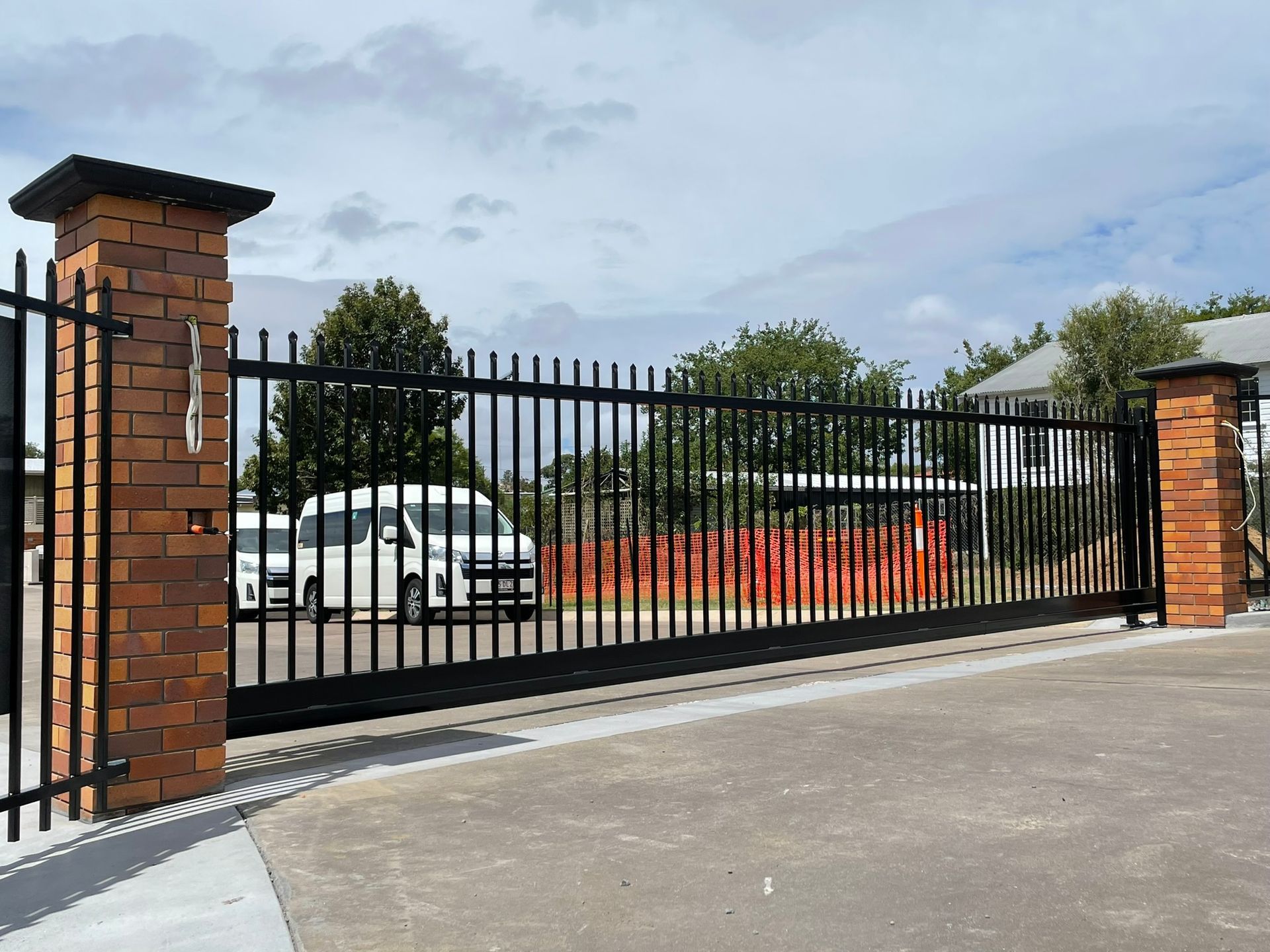A white van is parked behind a sliding gate
