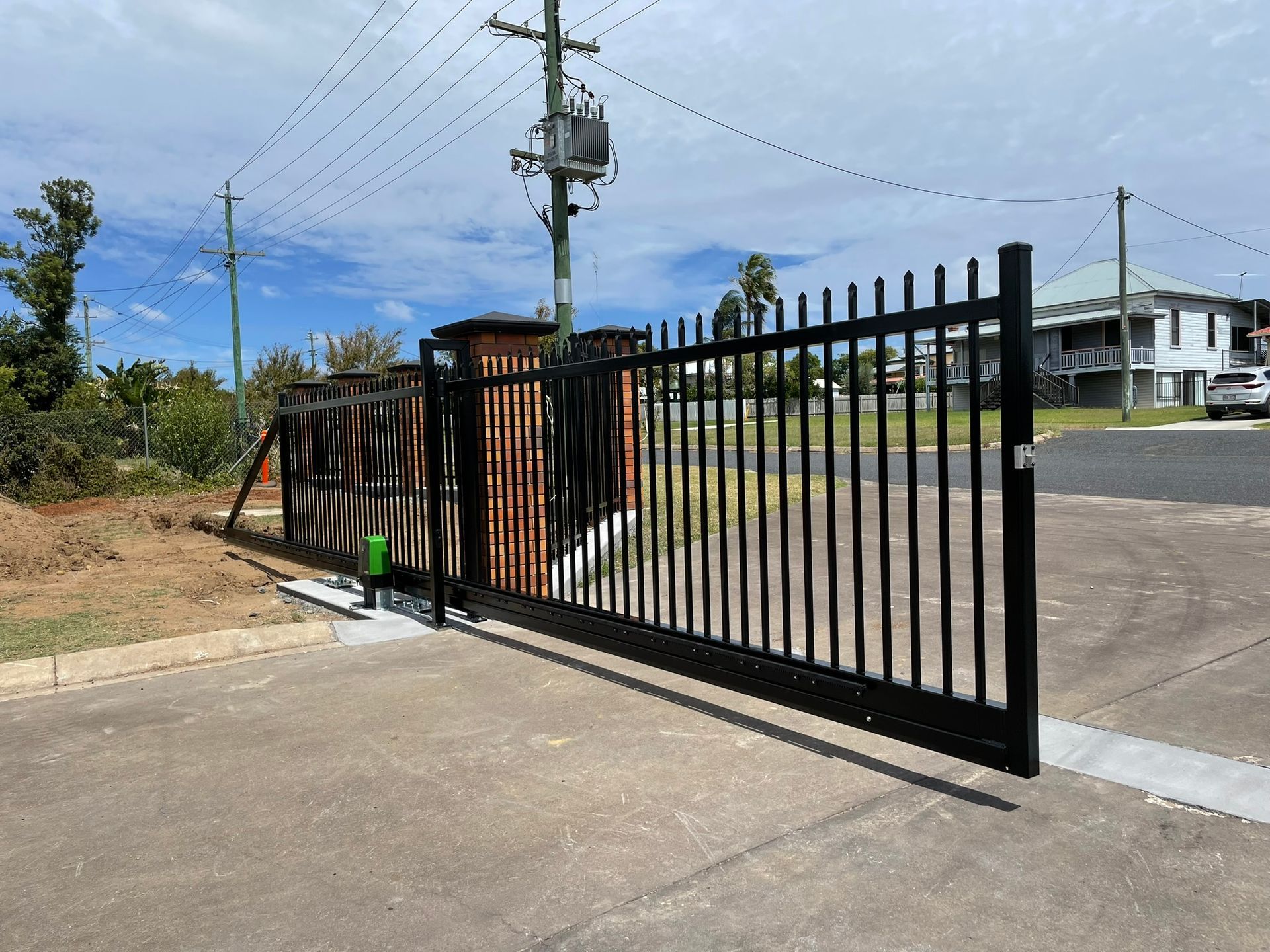 A black sliding gate is open in front of a house.