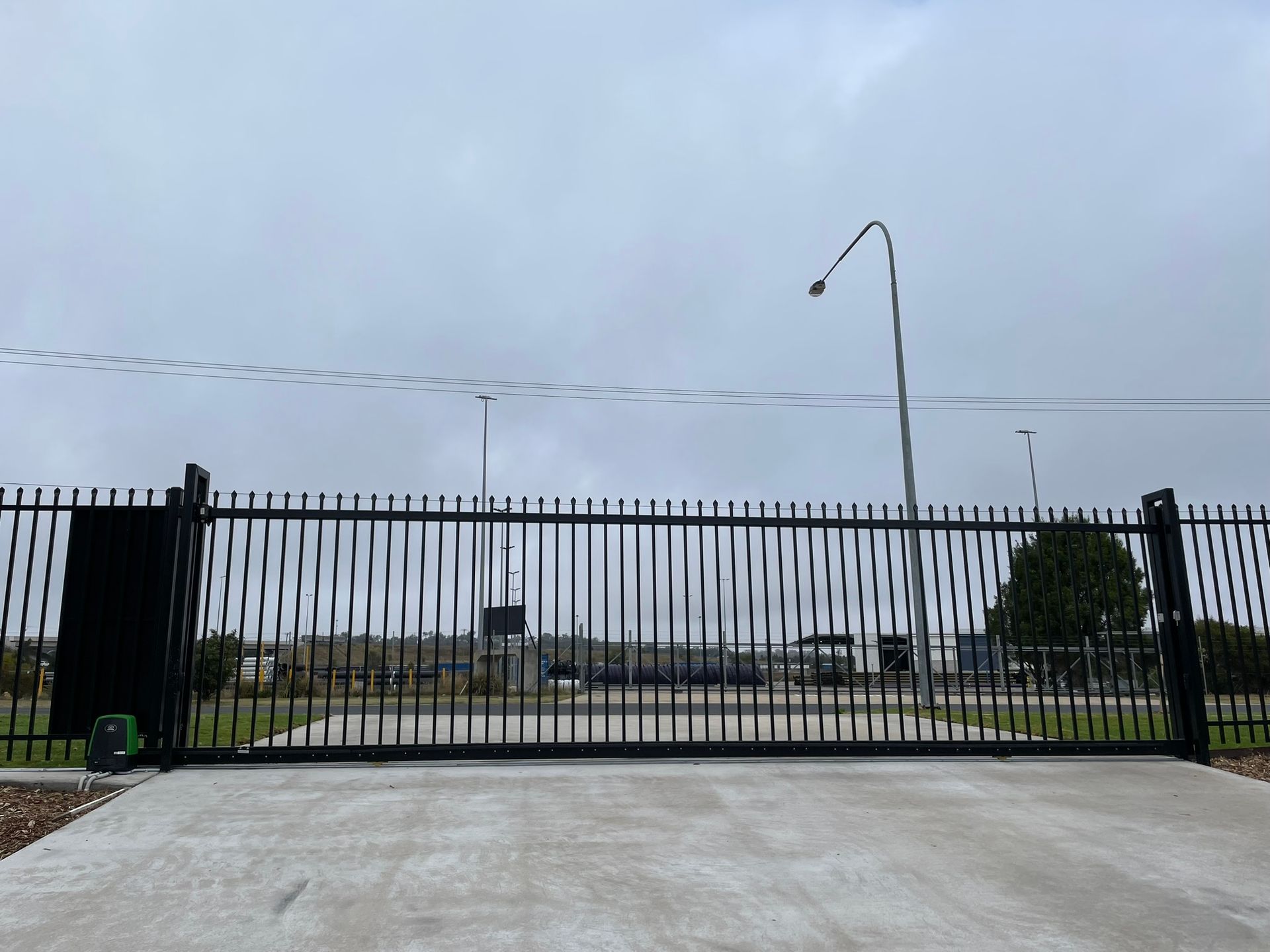 A large black gate is sitting on top of a concrete driveway.