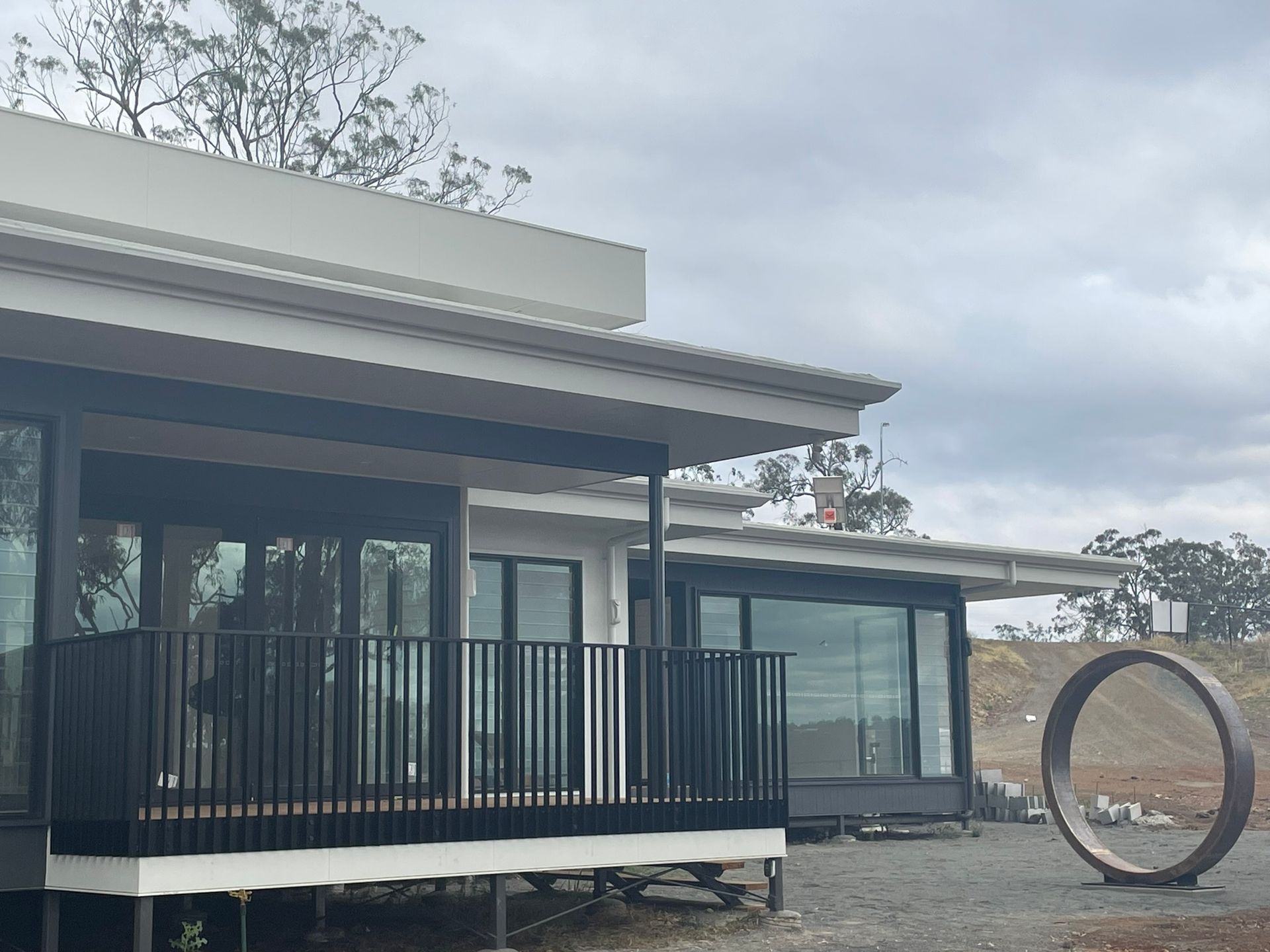 A house with a balcony and a sculpture in front of it.