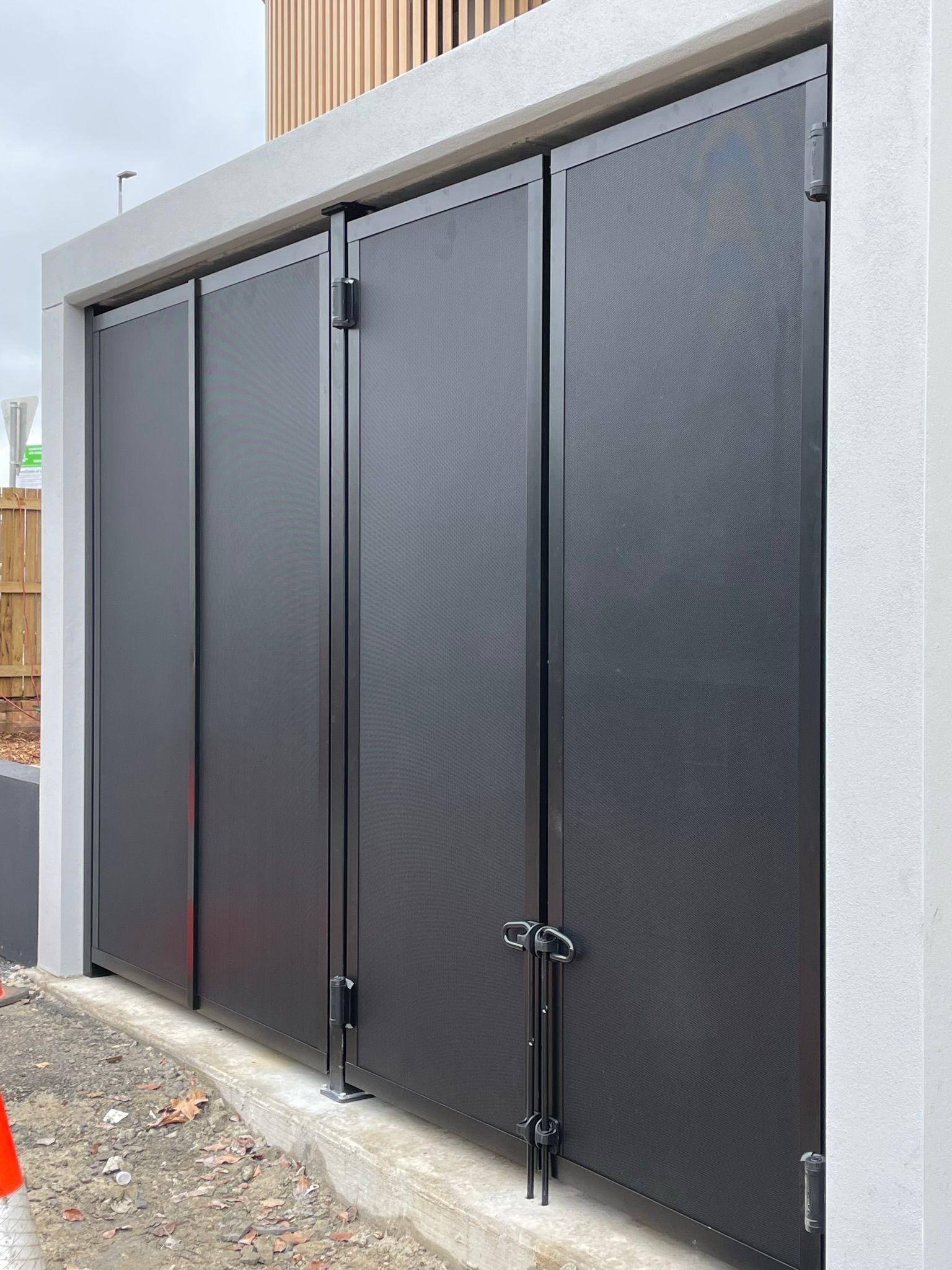 A row of black security doors sitting on top of a concrete wall.
