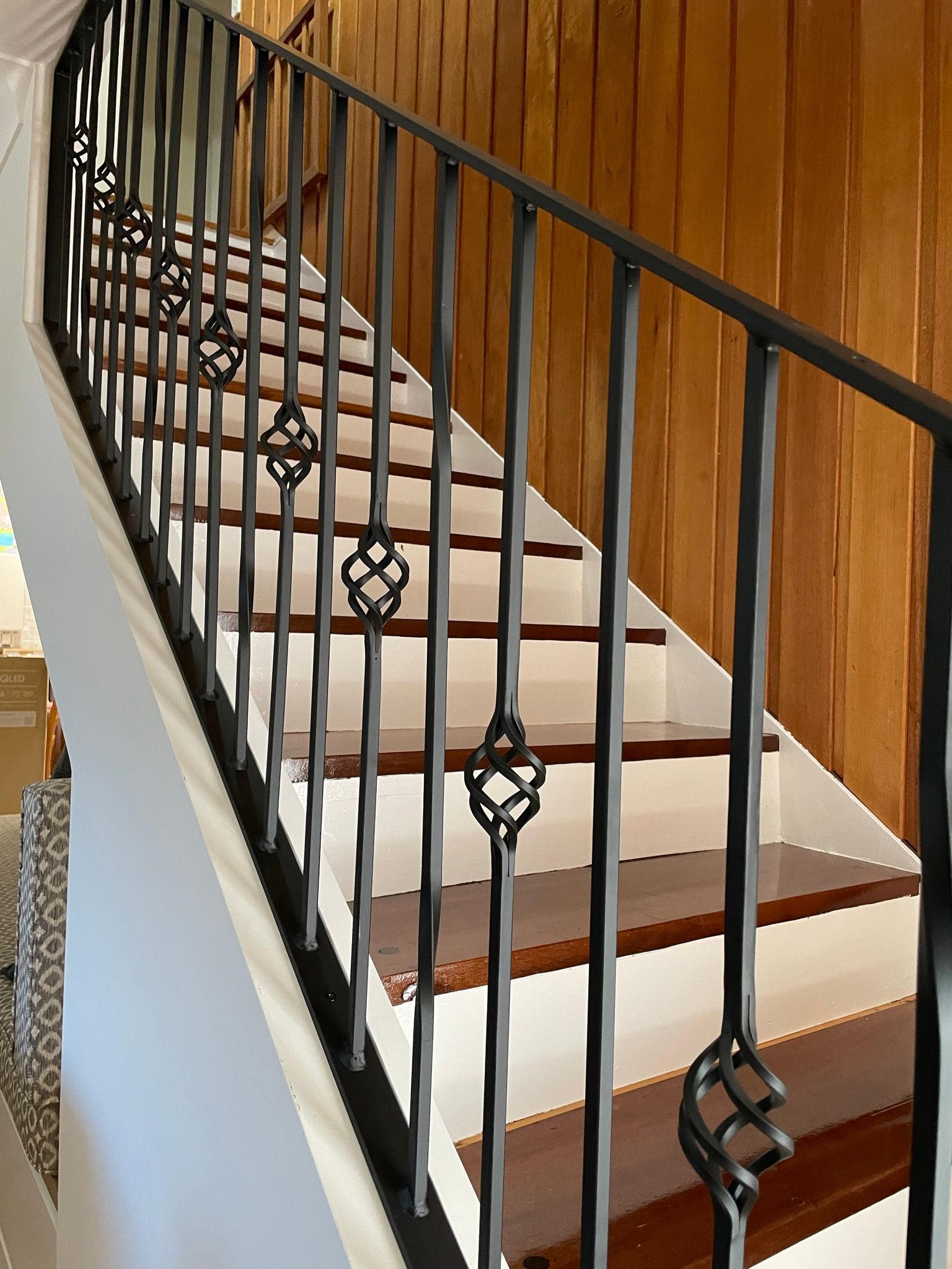 A staircase with a wrought iron railing and wooden steps