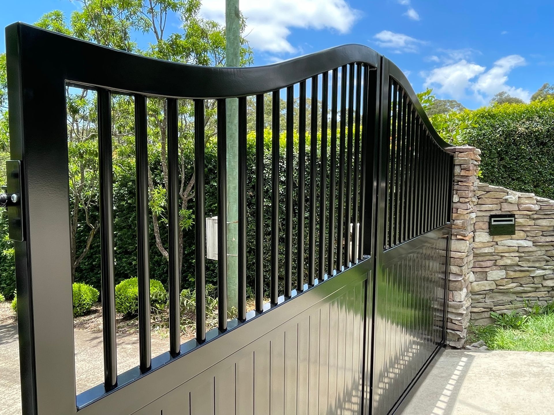 A black gate with a stone wall in the background