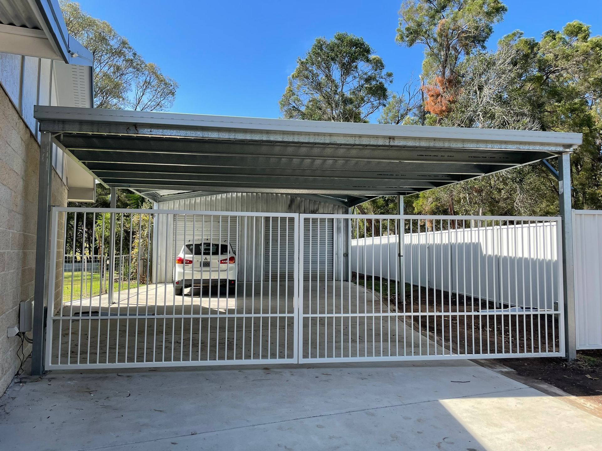 A car is parked under a canopy in a driveway