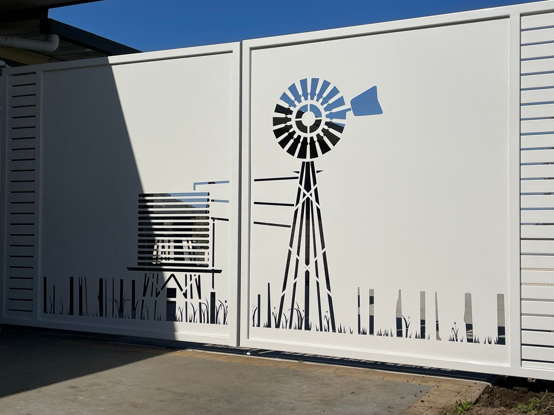 A white fence with a laser cut image of a windmill on it