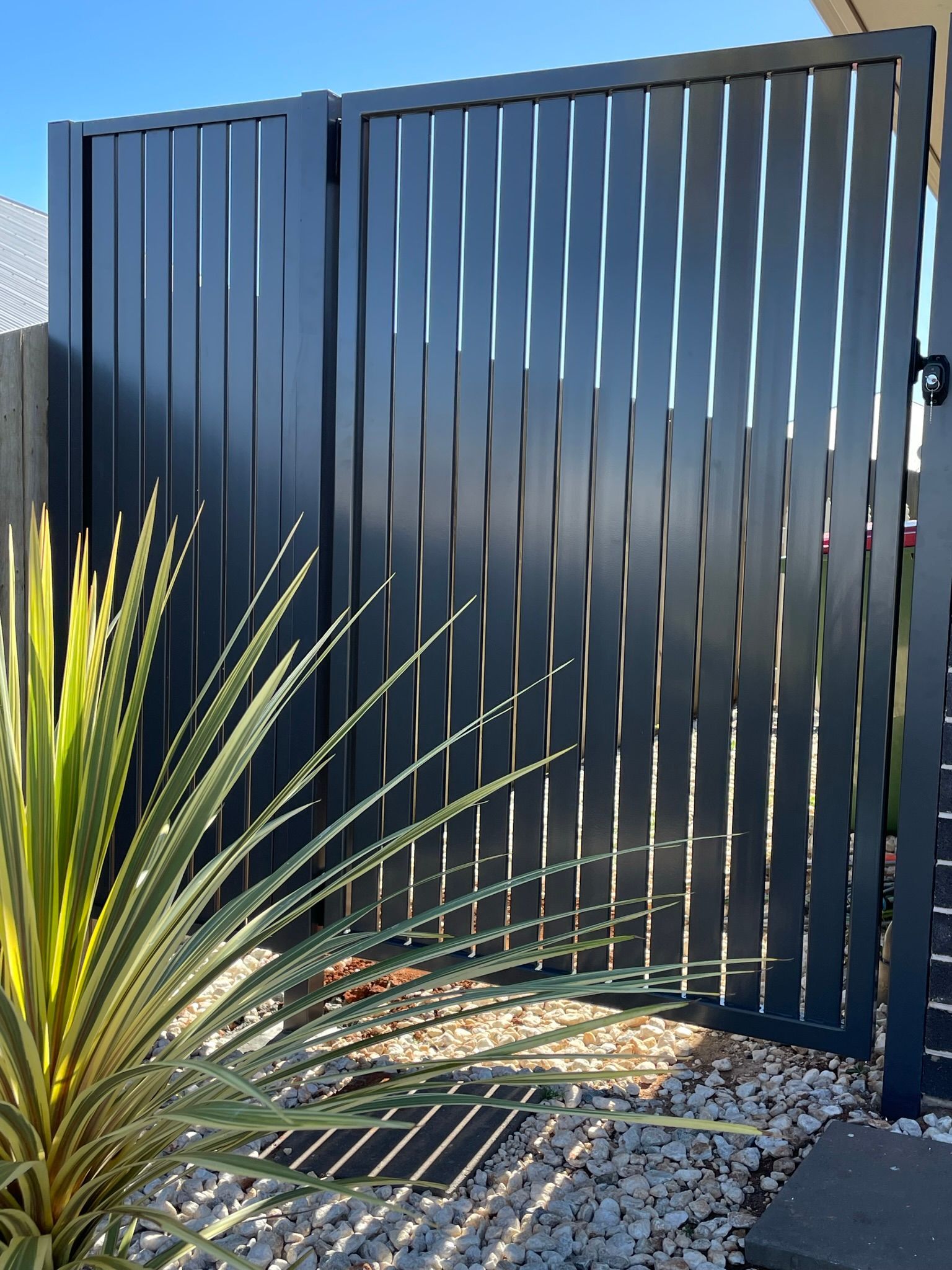 A black fence with a plant in front of it.