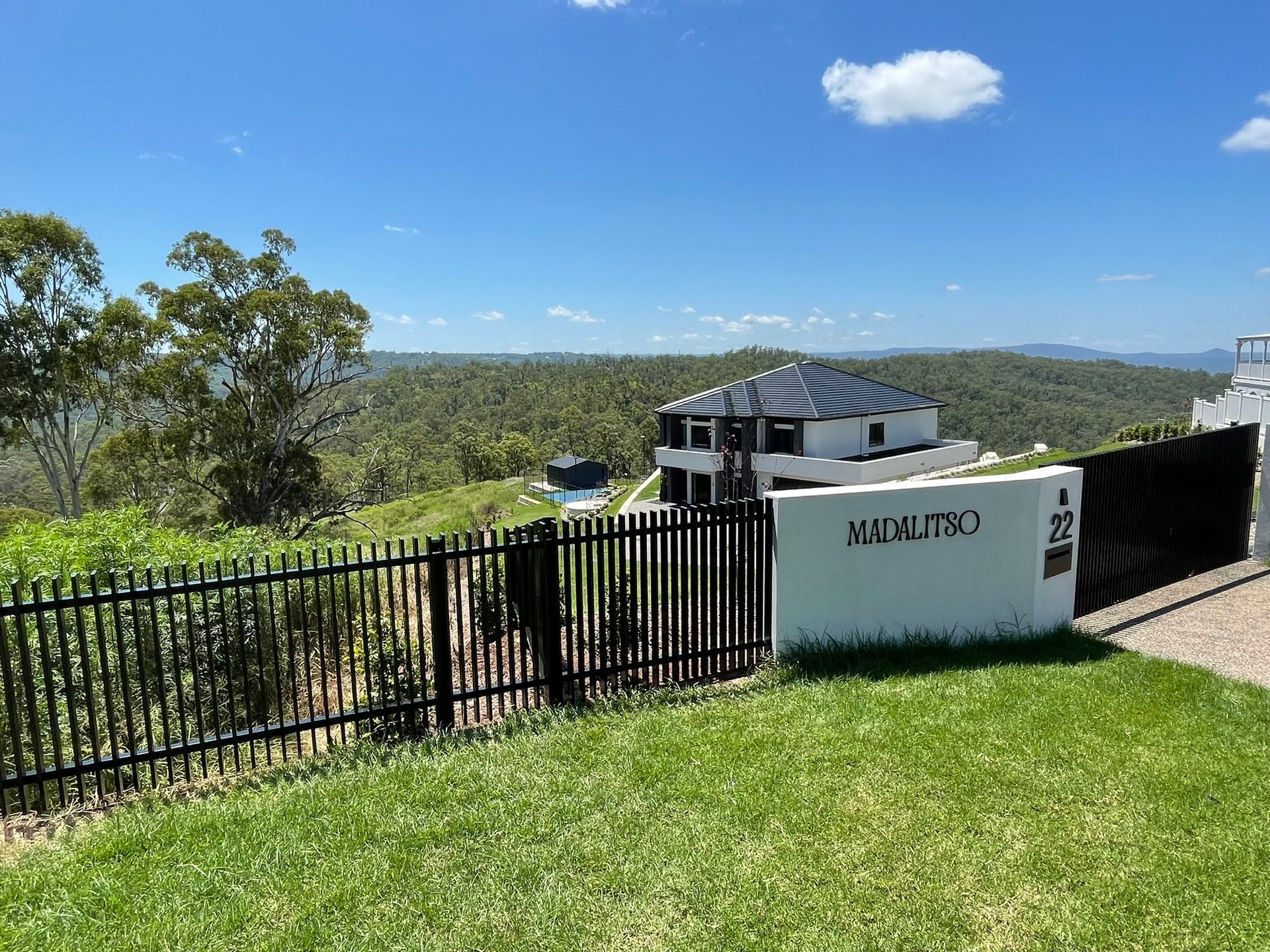 A house is behind a fence with a view of the mountains.