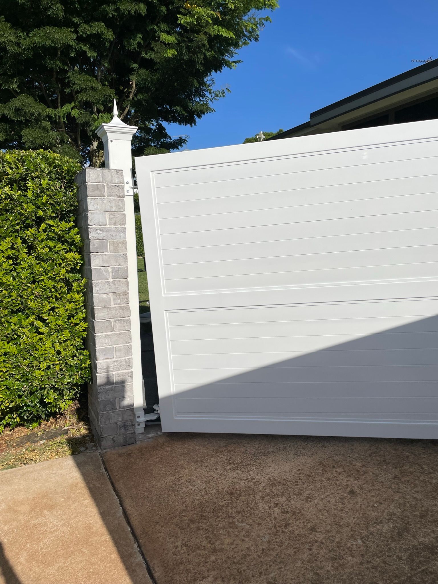 A white fence is sitting next to a brick wall.