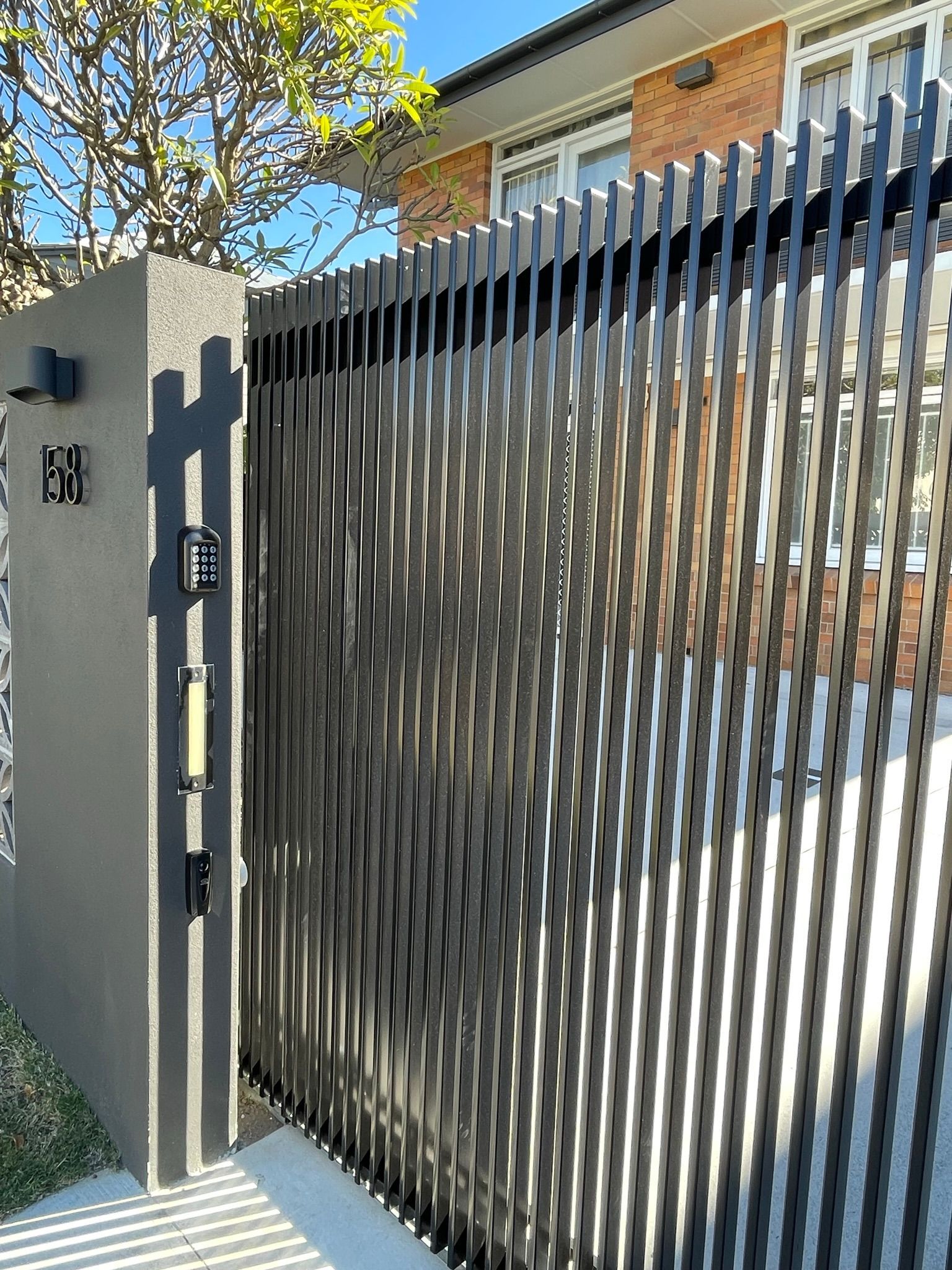 A close up of a fence with a gate in front of a house.