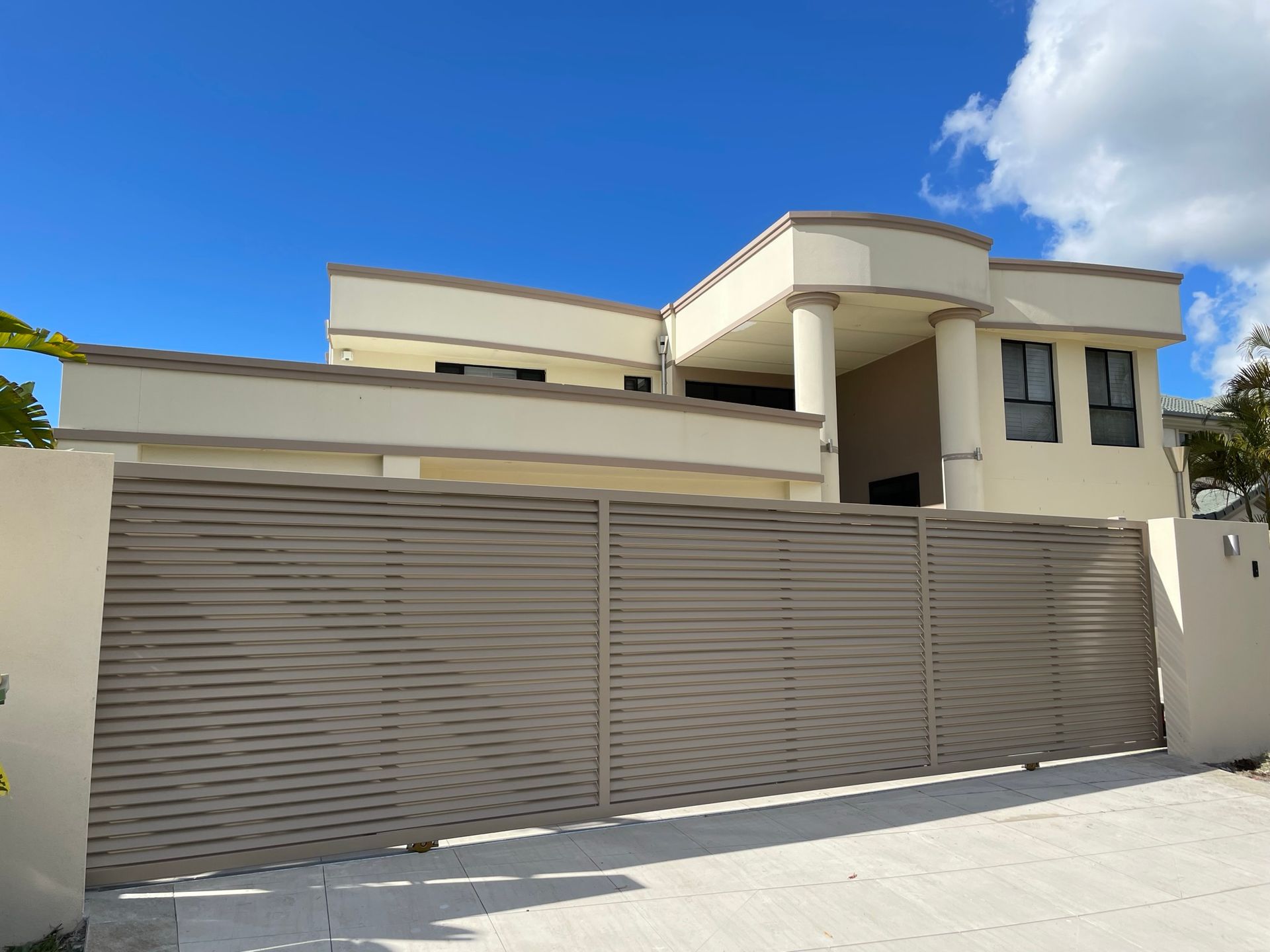 A large white house with a sliding gate in front of it