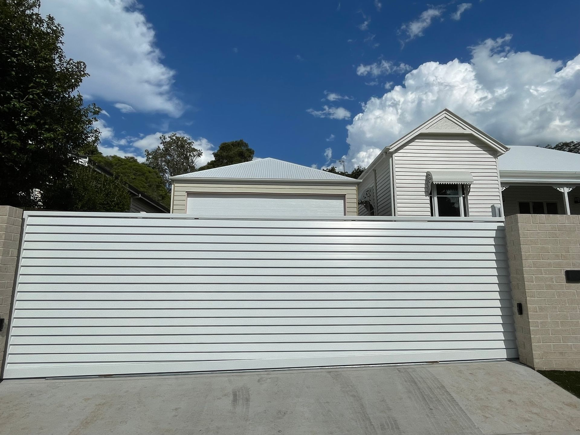 A white house with a sliding gate in front of it