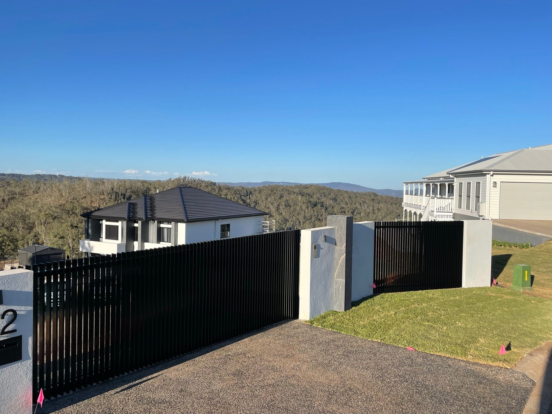 A black fence is surrounding a house on a hill.