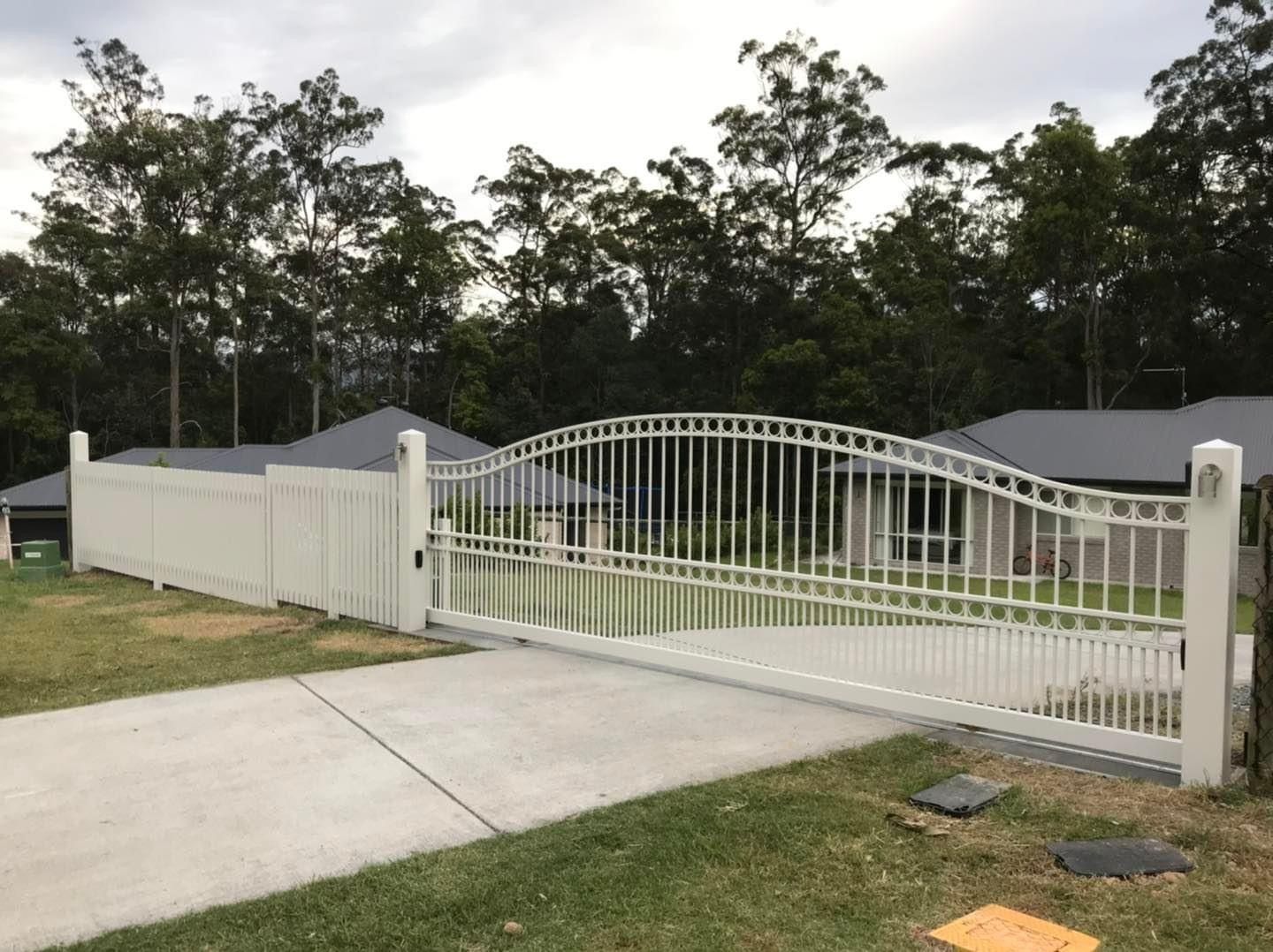 A white fence with a gate in front of a house