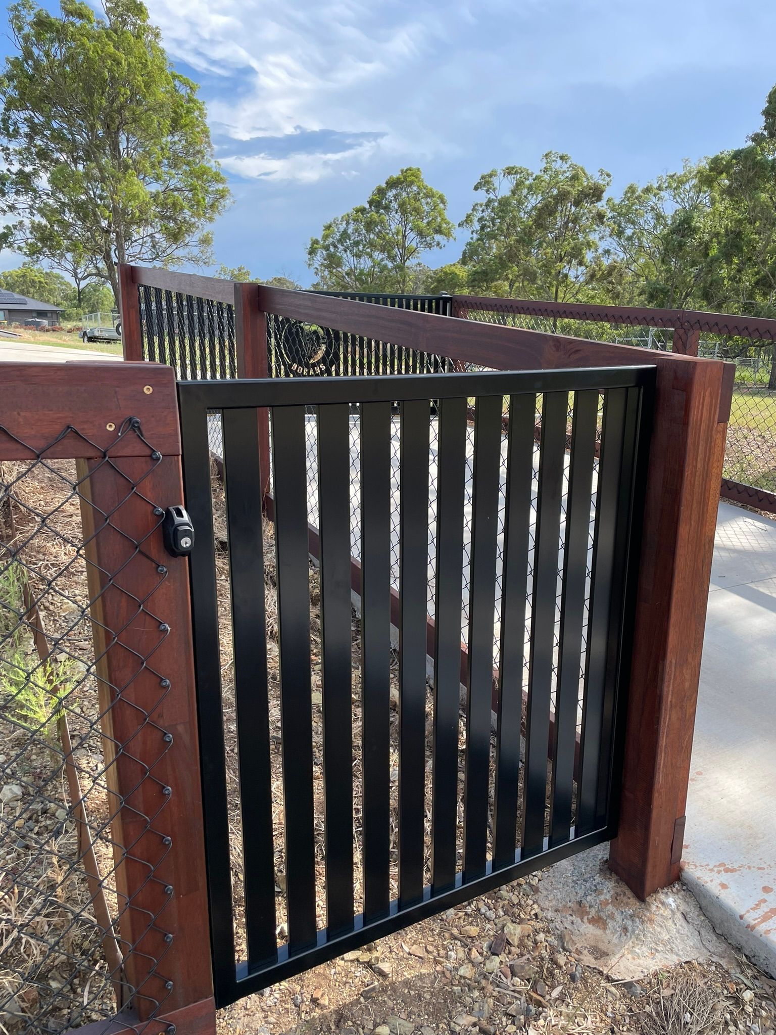 A white gate is sitting in the middle of a gravel road.