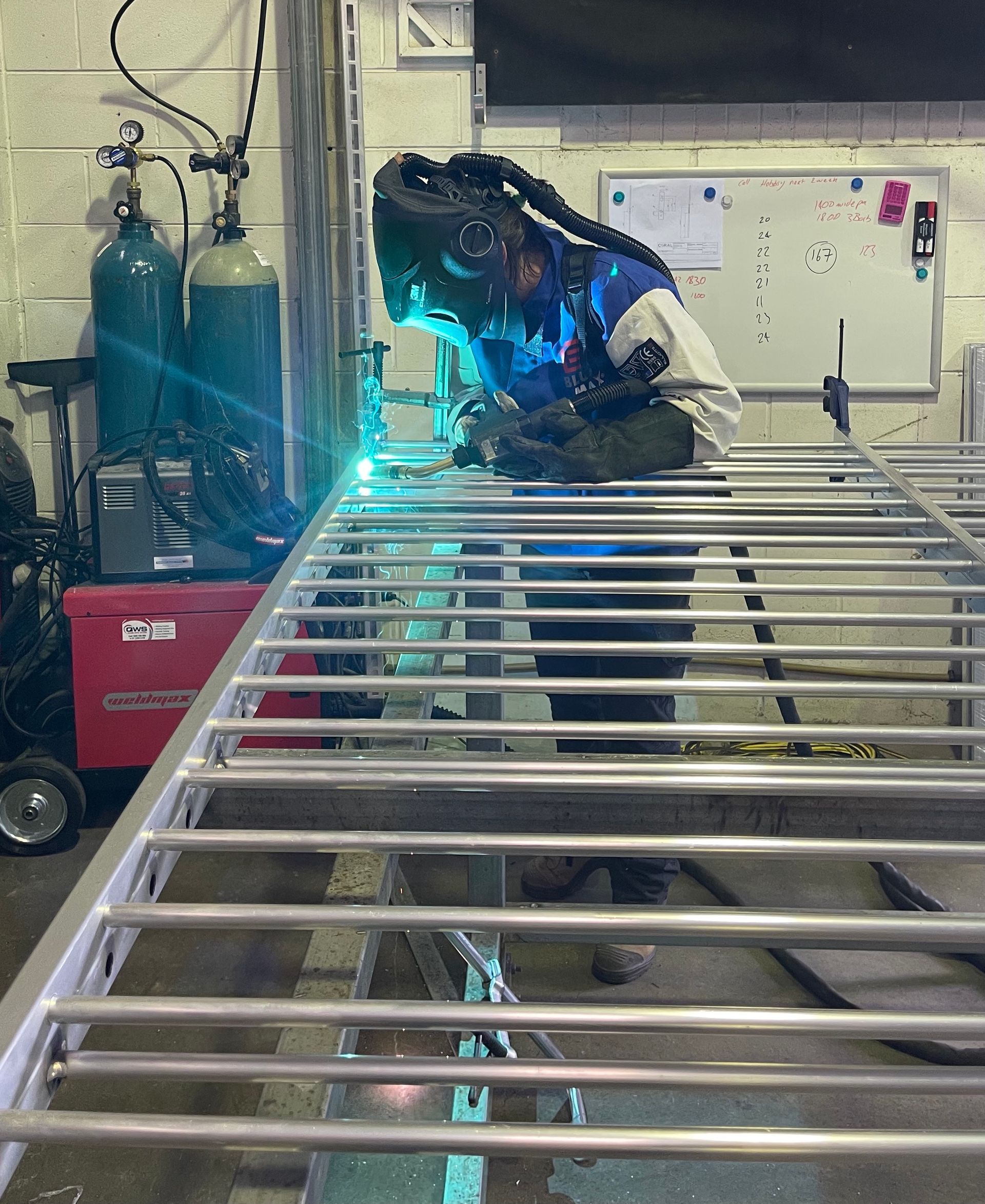 A person is welding a metal gate in a workshop.