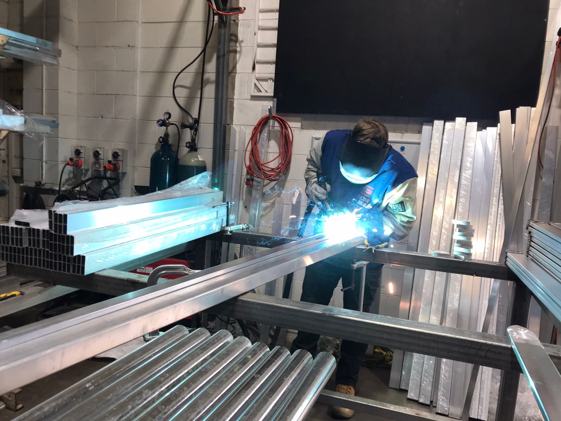 A person is welding a metal gate in a workshop.