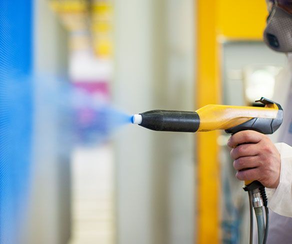 A powder coating spray gun is painting a custom built gate.