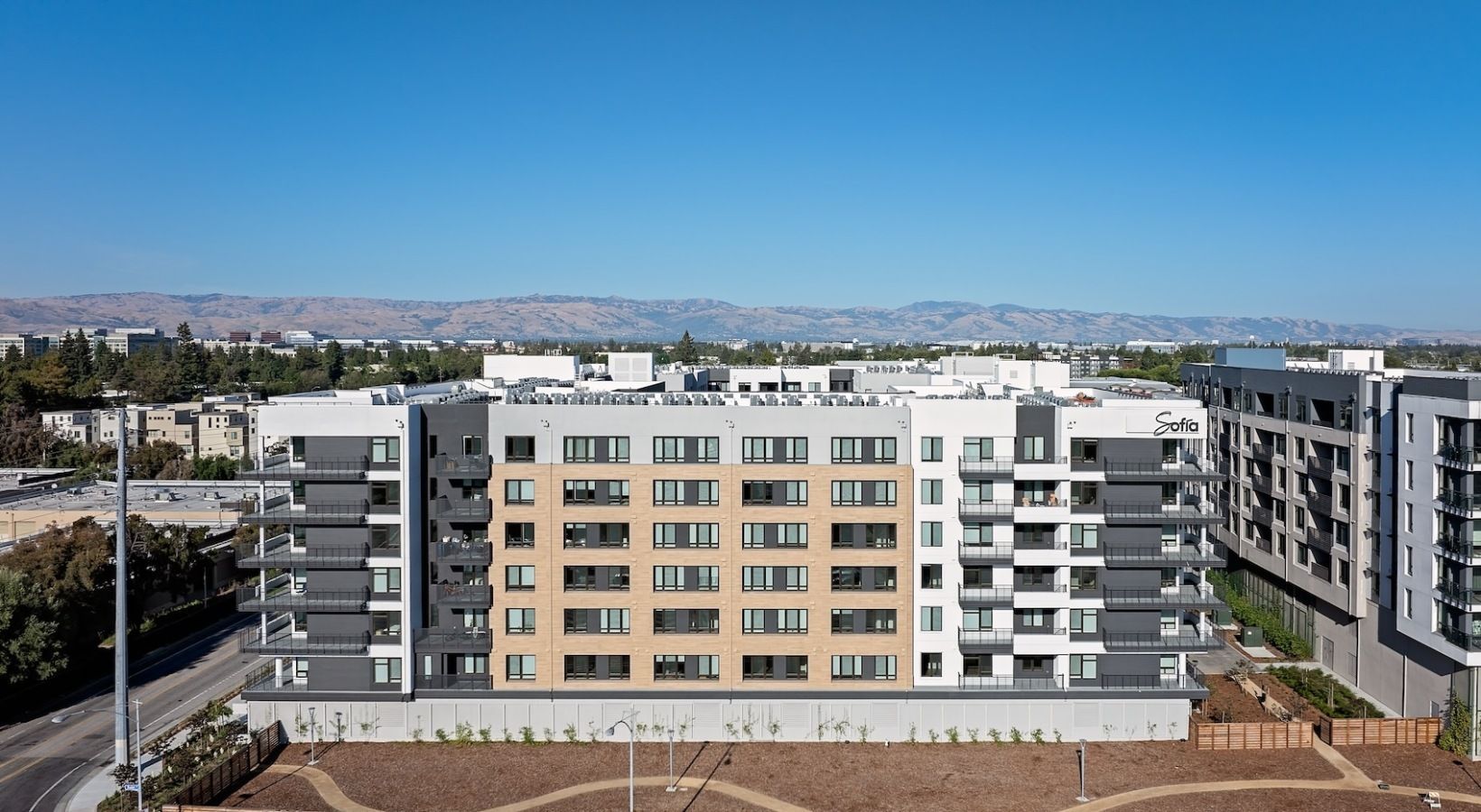 Exterior view of a modern apartment complex with multiple mid-rise buildings and balconies under a blue sky at Sofia.