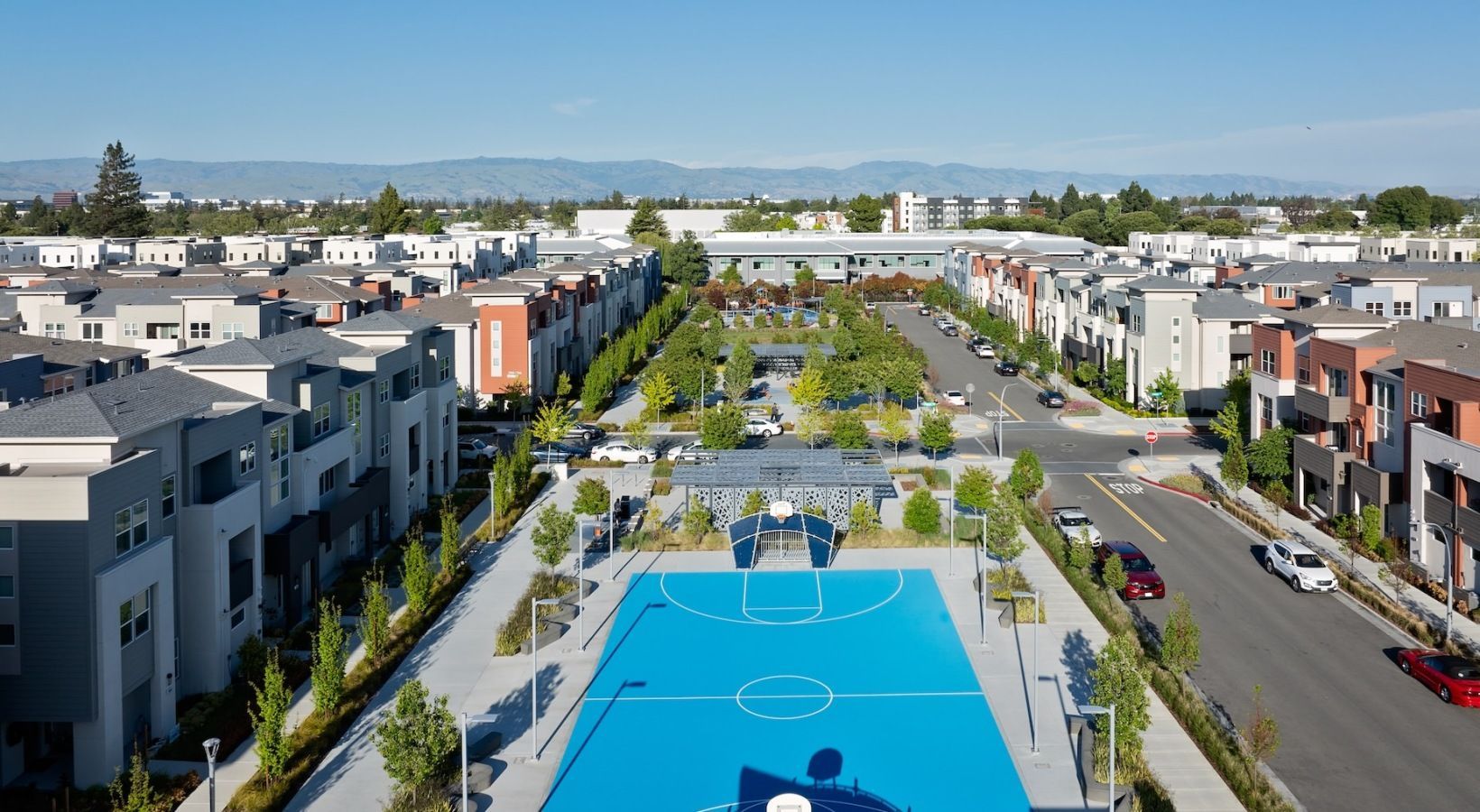 Aerial view of a modern apartment community with a blue basketball court and central plaza at Sofia, offers Santa Clara apartments for rent in CA.
