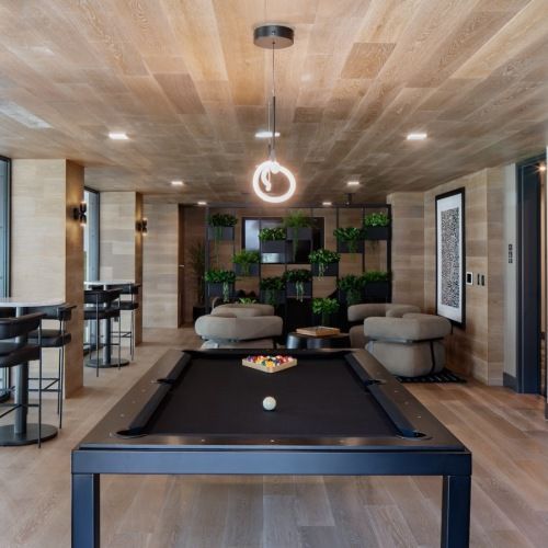 Indoor community lounge with a billiards table, surrounding seating, and indoor plants at Sofia, offers  pet-friendly apartments in Santa Clara.