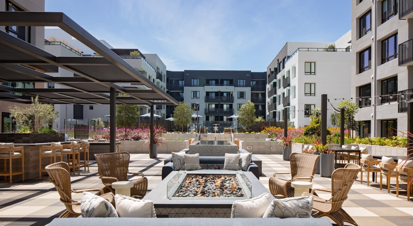 Modern apartment courtyard with a central fire pit, lounge seating, and surrounding buildings at Sofia, offers apartments for rent in Santa Clara, CA.