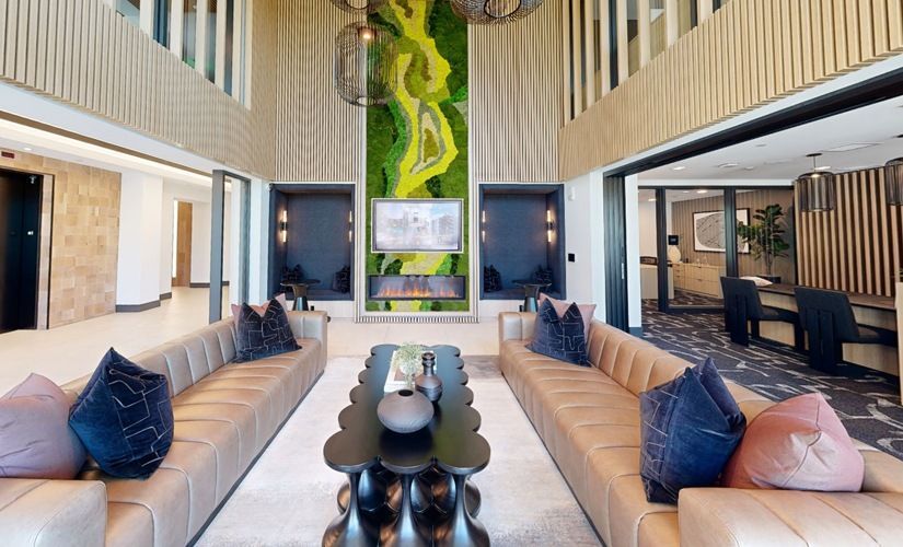 Indoor resident lounge with tan sectional sofas, dark coffee tables, and a vertical moss wall at Sofia, offers  pet-friendly apartments in Santa Clara.