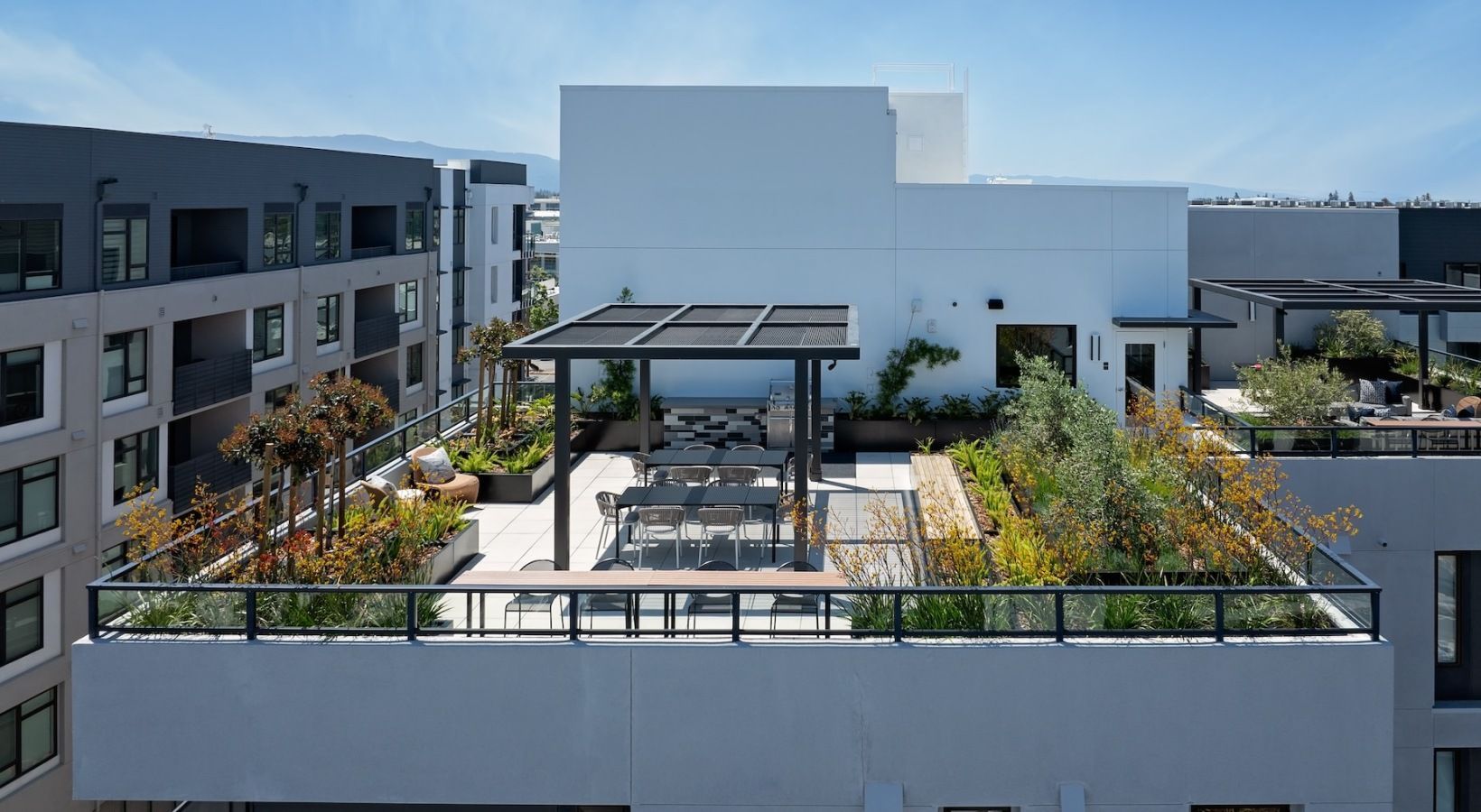Rooftop communal terrace with seating, a pergola, and planter beds on a modern apartment building at Sofia in Santa Clara, CA.