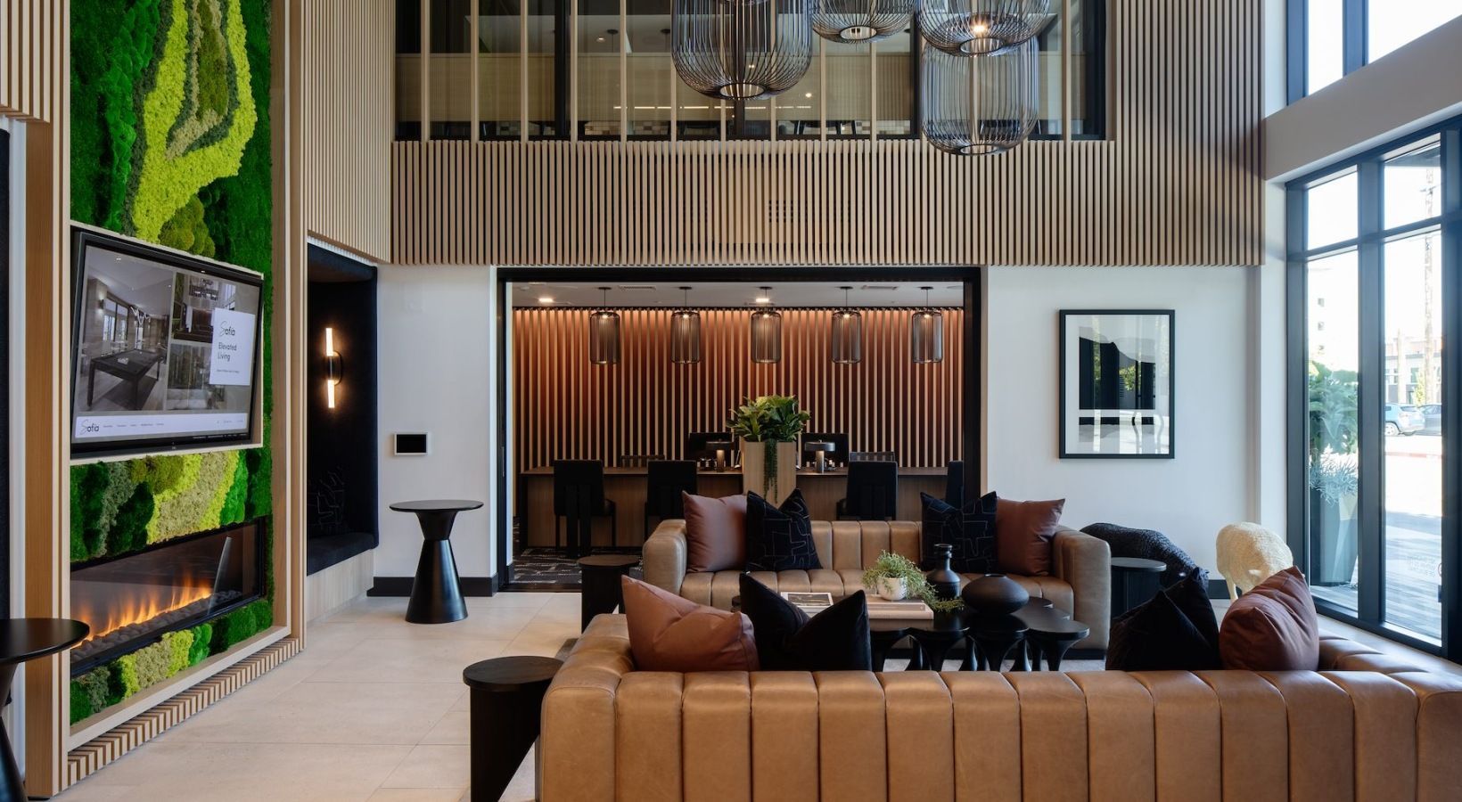 Modern apartment lobby with tan leather sofas, wood slat walls, and greenery at Sofia, offers Santa Clara apartments for rent in CA.