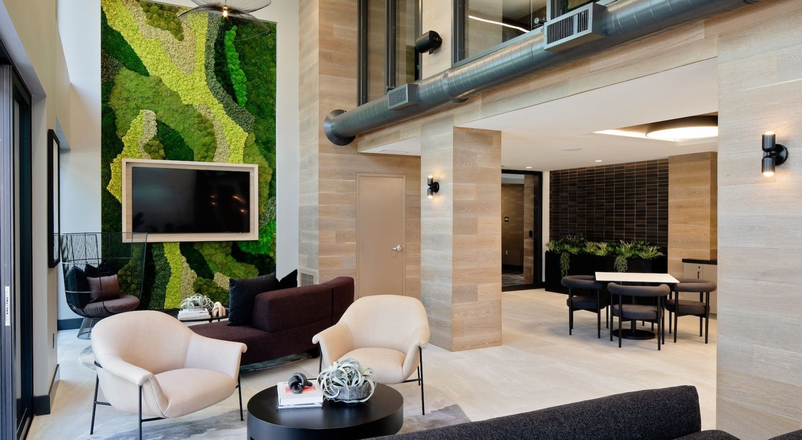 Modern residential lobby with green moss wall, TV, and seating area at Sofia, offers Santa Clara apartments for rent in CA.