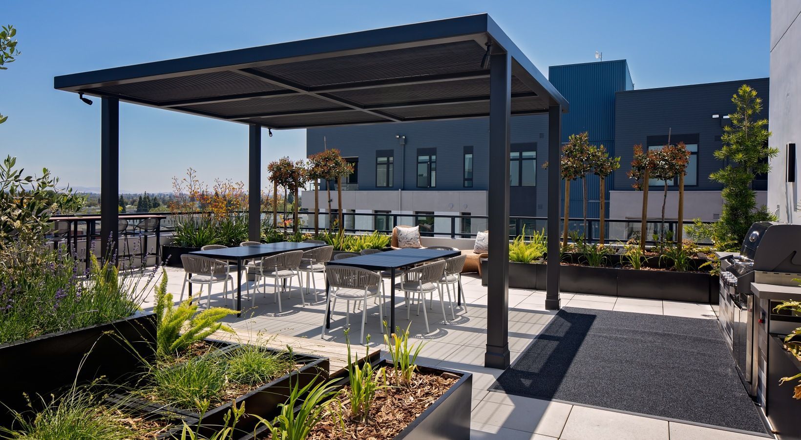 Rooftop terrace with a metal pergola, dining tables, chairs, and landscaped planters at Sofia, offers Santa Clara apartments for rent in CA.
